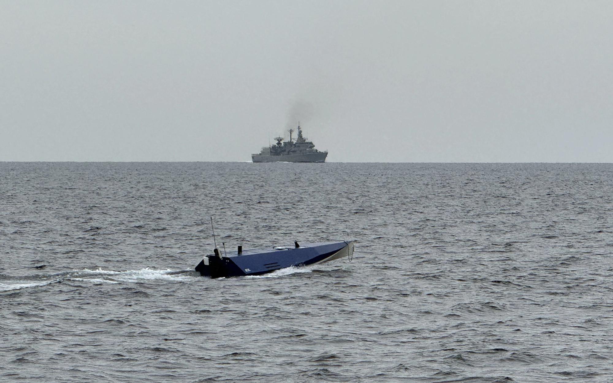 USV running at sea with a naval escort vessel visible on the horizon