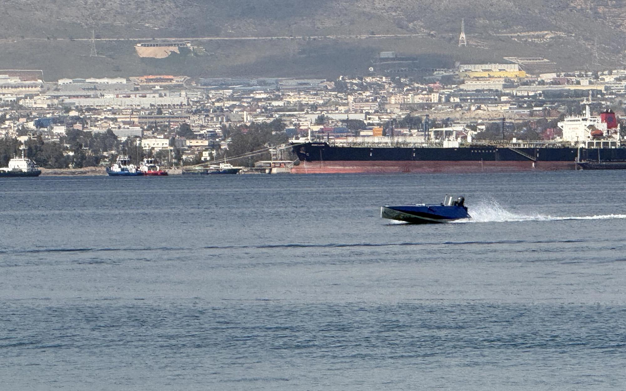 ER69D running at speed on open water, Saronic Gulf coastline in the background