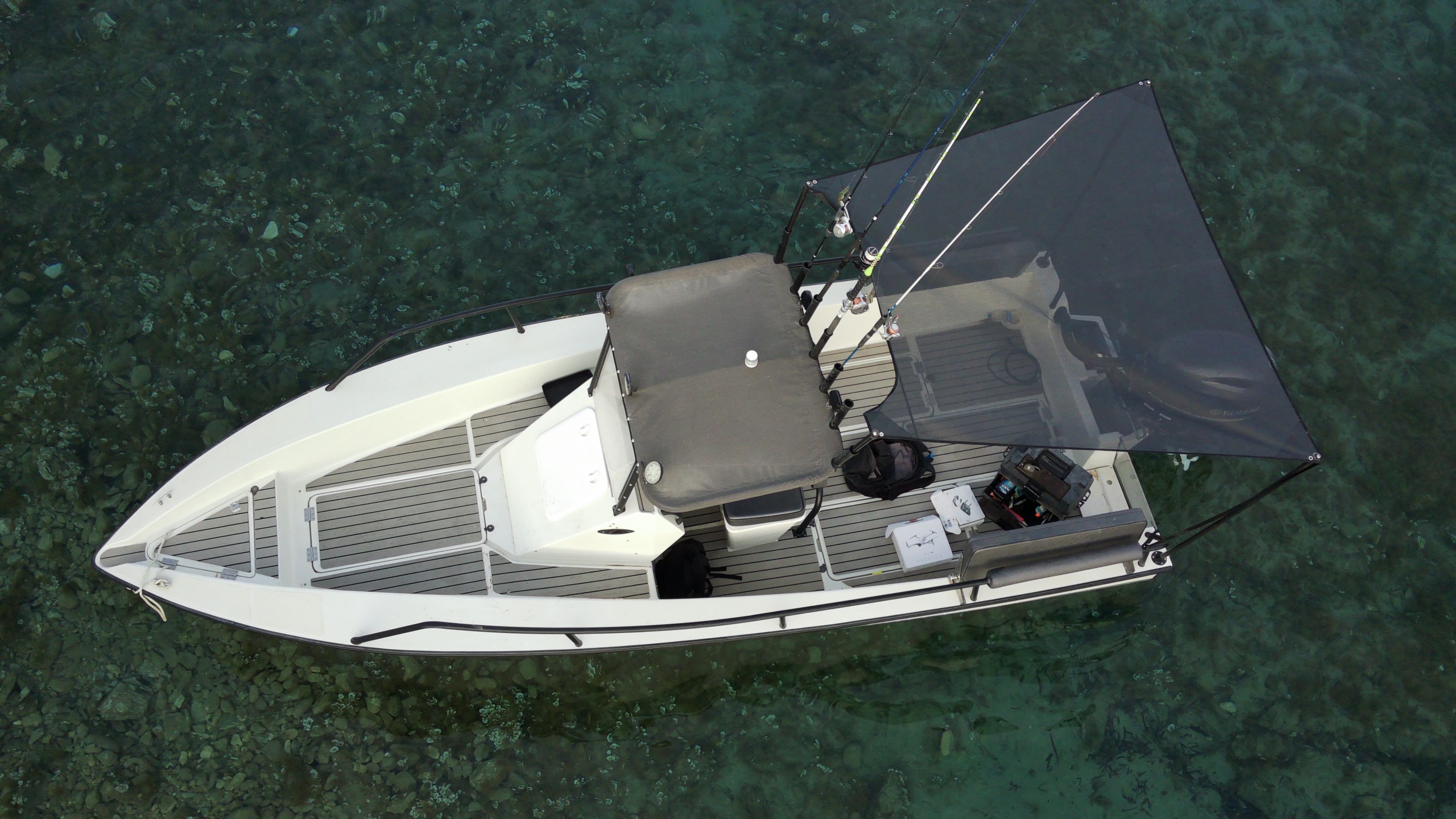 EcoRunner 59 Gen2 anchored over a shallow reef, top-down aerial view, fishing gear on deck