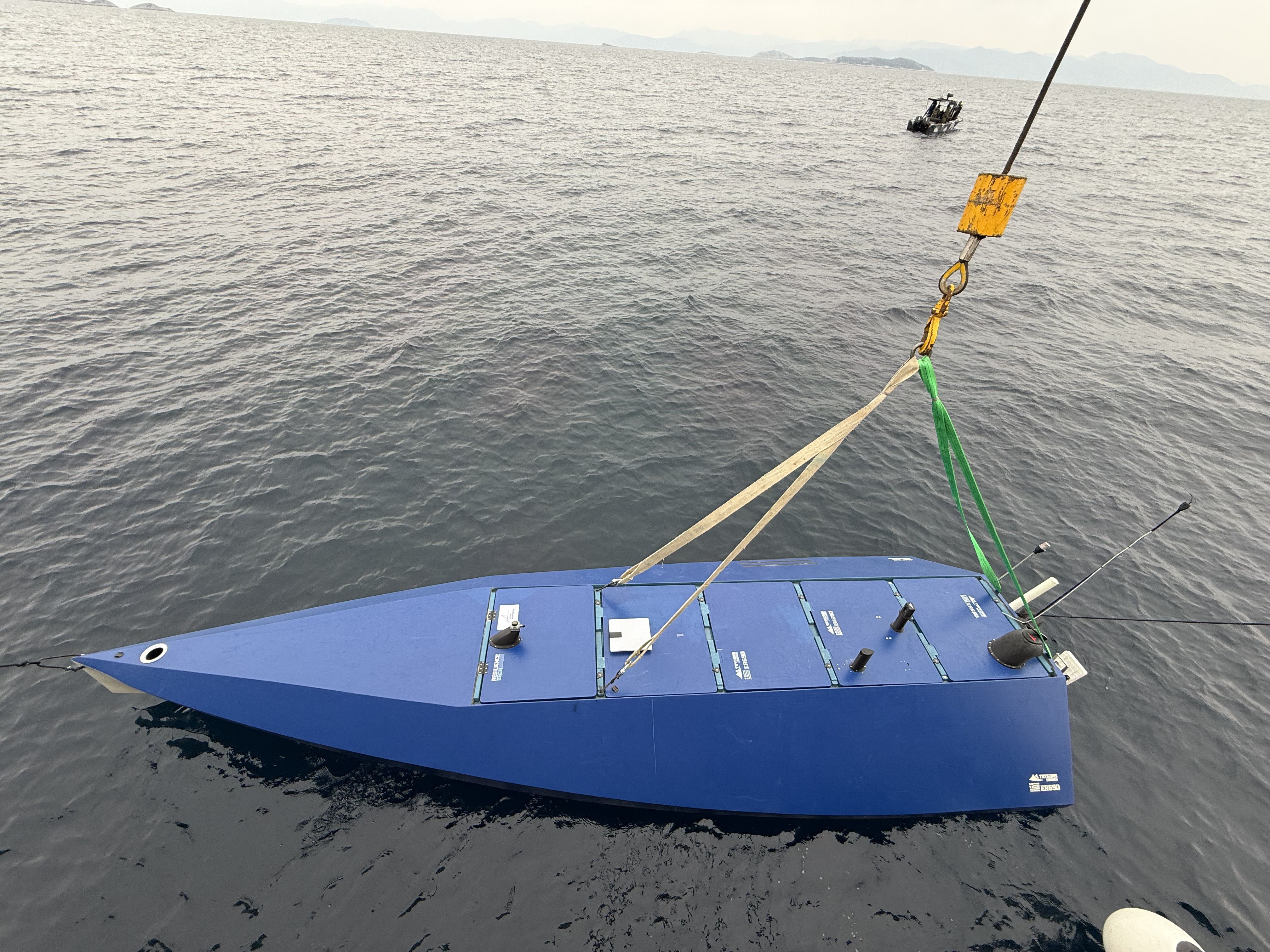 ER69D unmanned surface vehicle lifted from the water by crane during a field trial, dusk