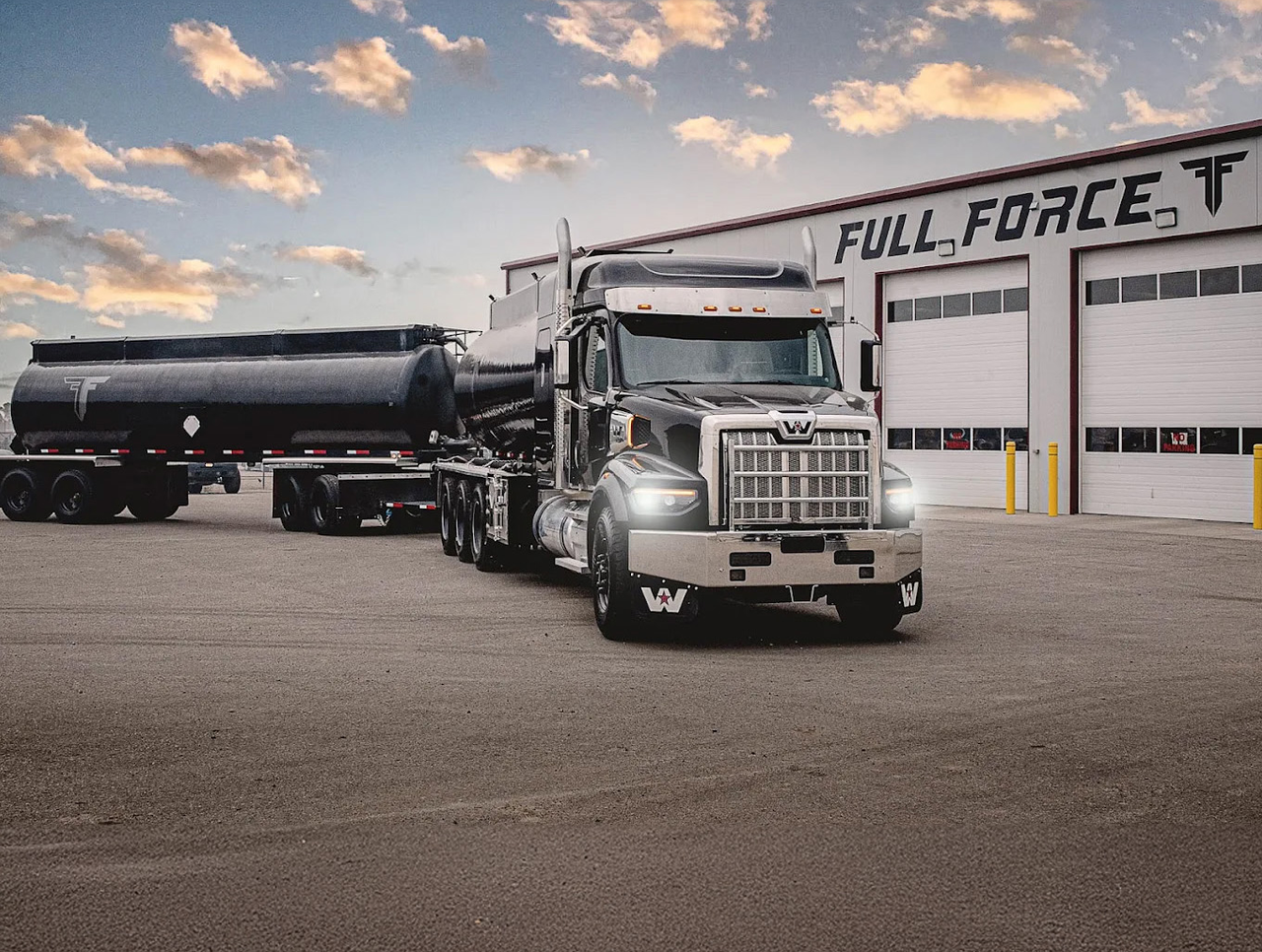 A black and chrome semi-truck is parked in front of a multidoor commercial garage with Full Force Ventures printed across the building.