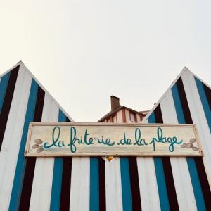 wooden houses painted lightblue, darkblue and white, with a sign that says la friterie de la plage