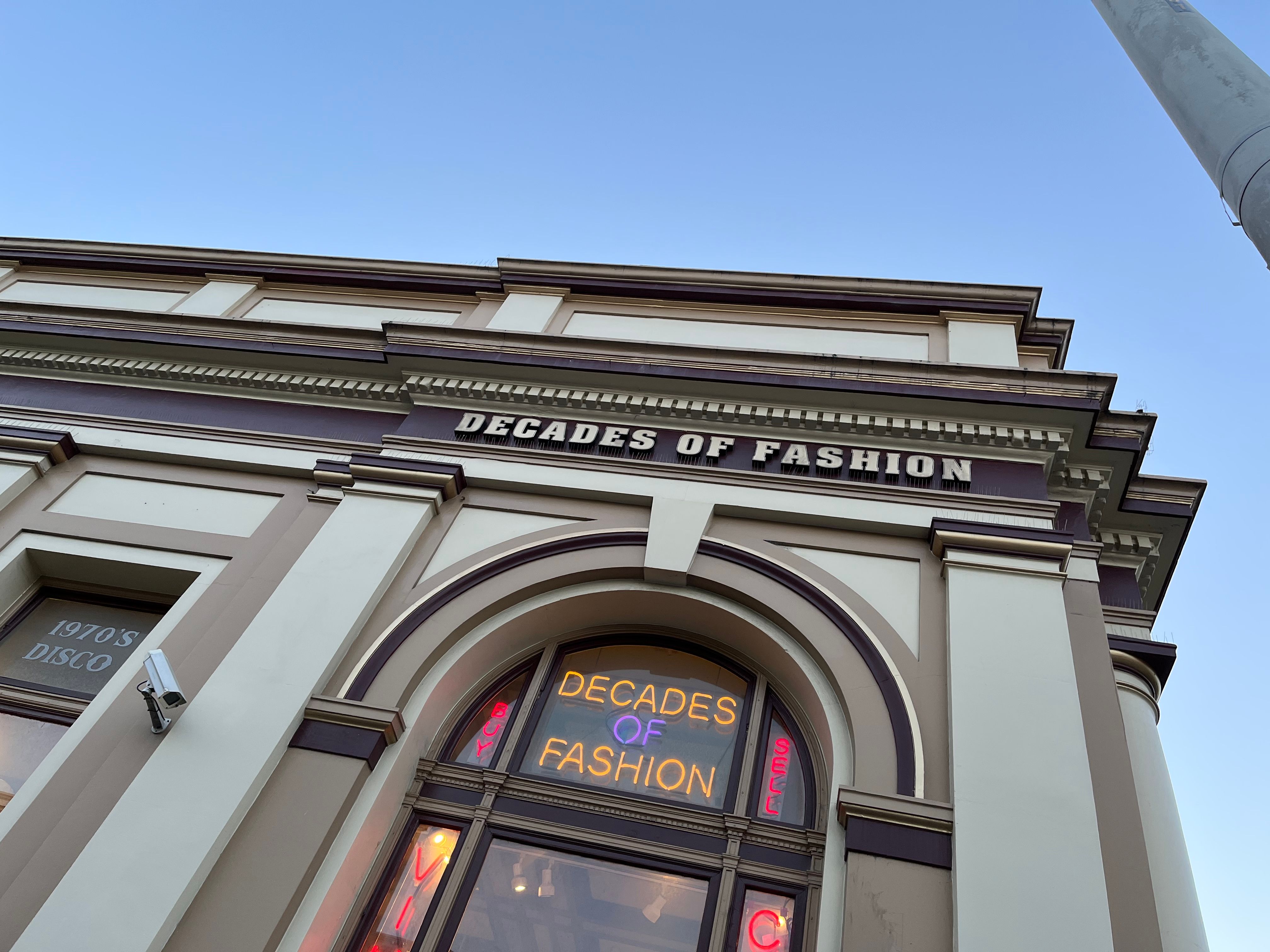 storefront that says decades of fashion in neon