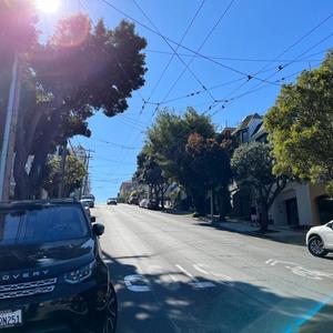 steep street with parked cars and a sunny blue sky 