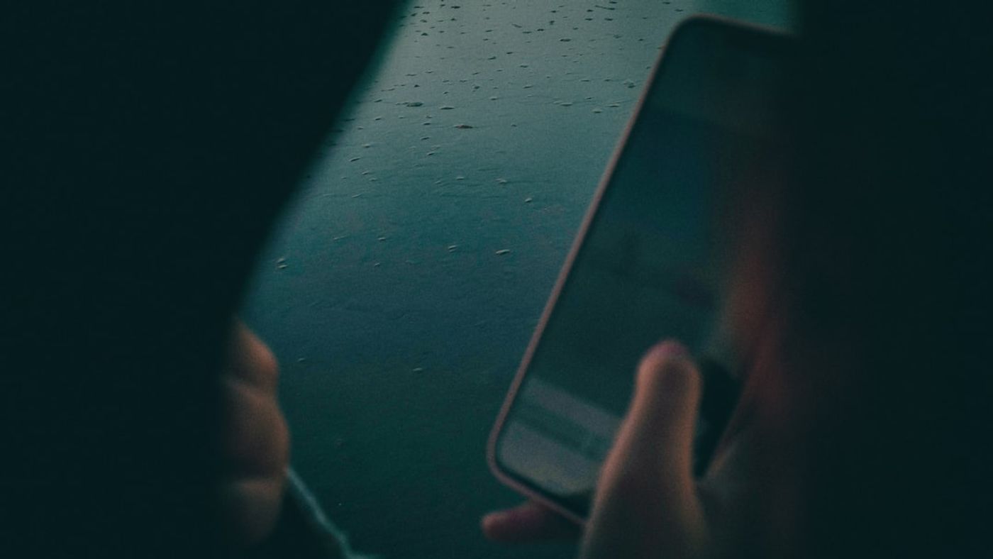 Person scrolling on a phone while working at a desk