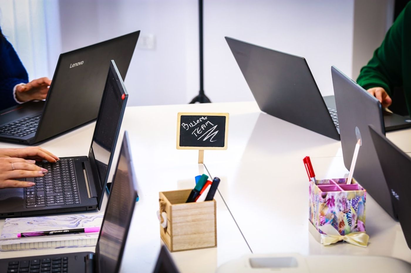 Team collaborating at a desk with laptops (community engagement workflow)