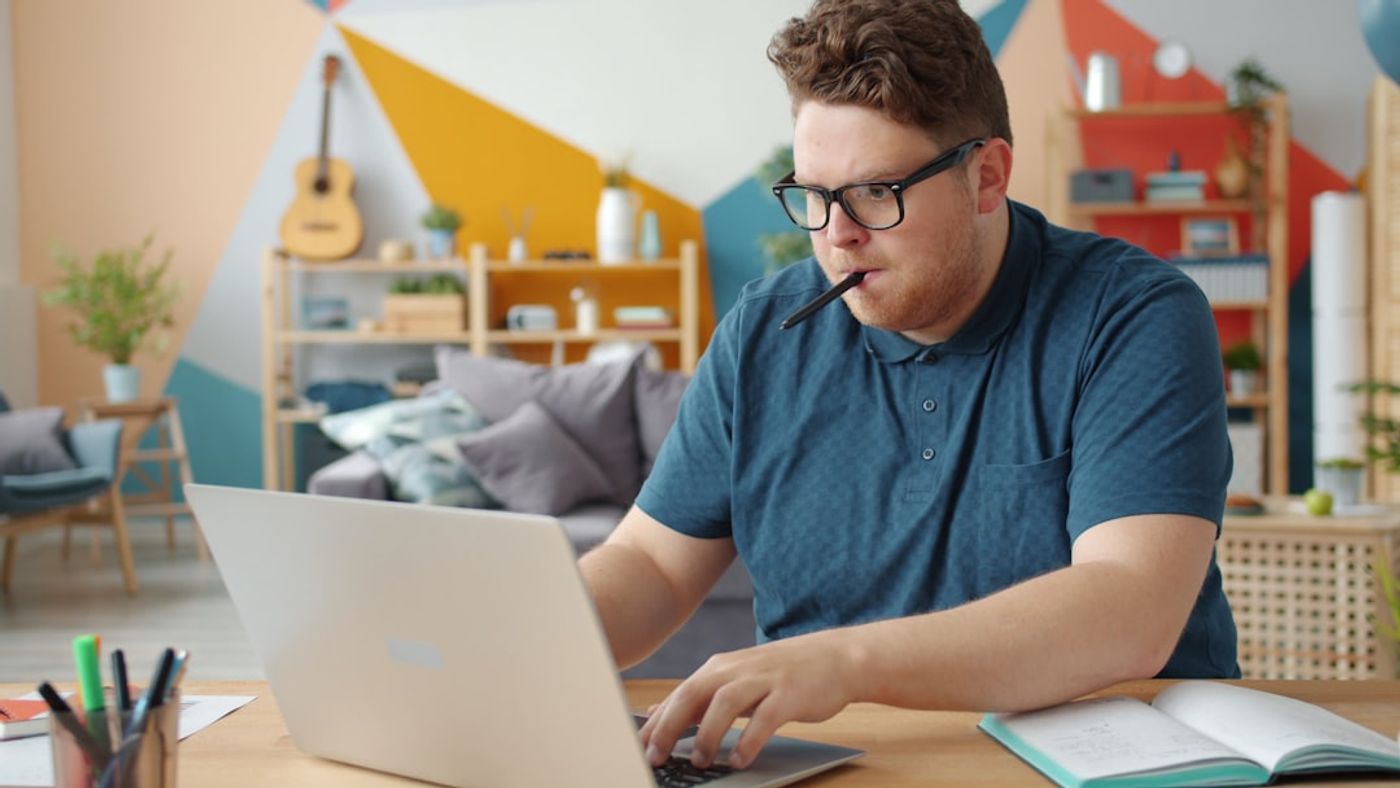 person working on a laptop writing notes with a checklist