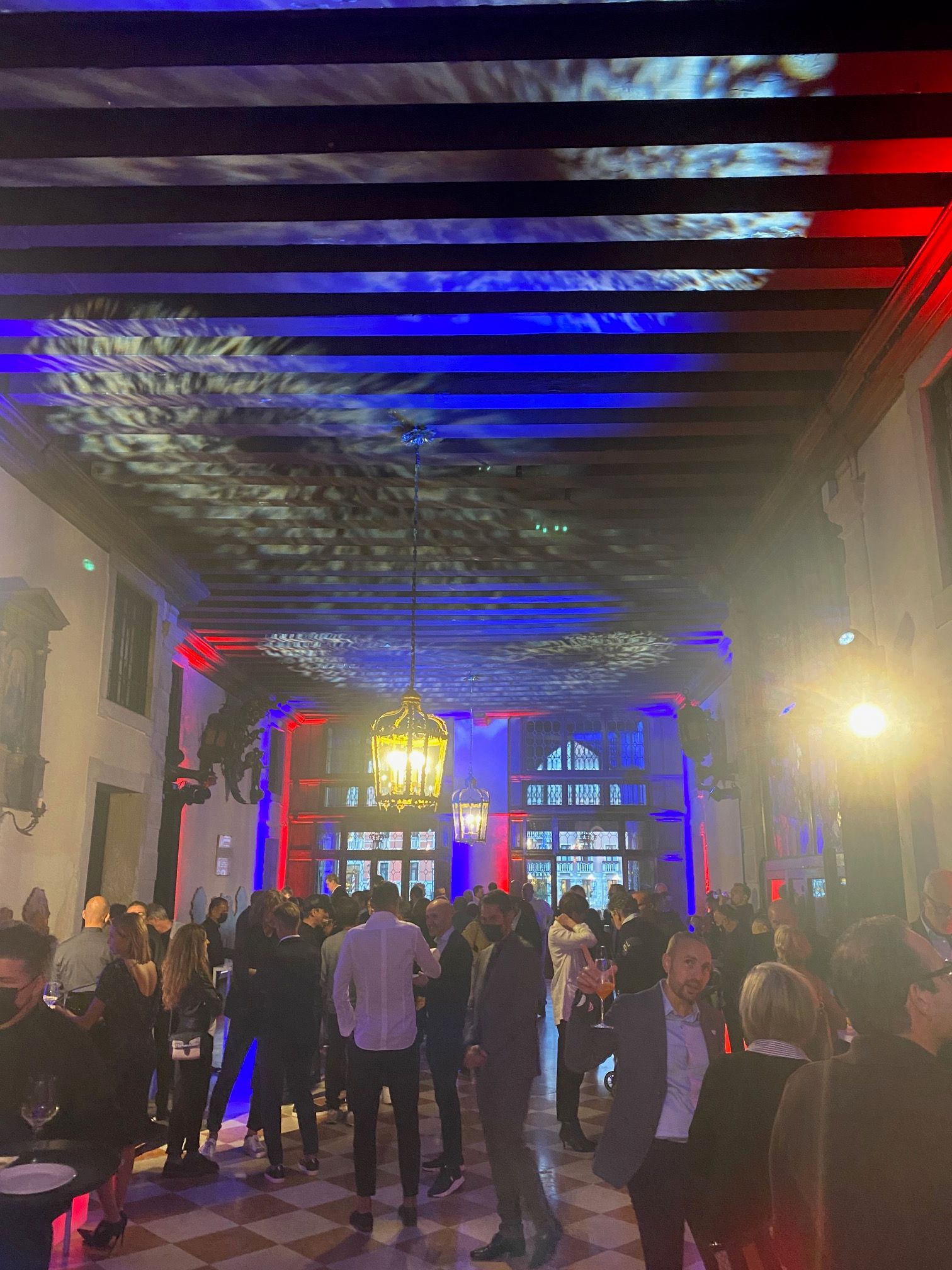 sala di un palazzo veneziano illuminata da luci colorate con persone 