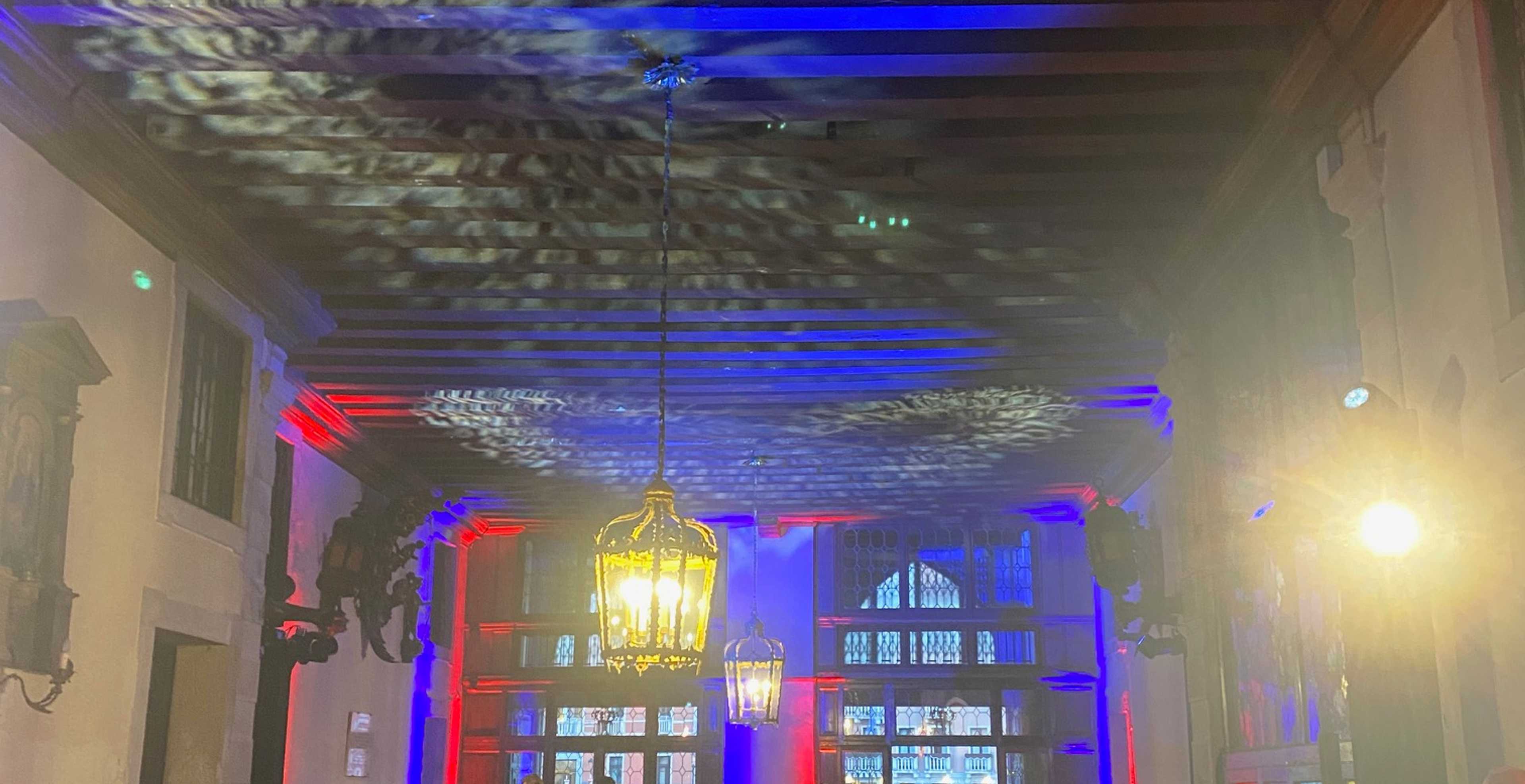 sala di un palazzo veneziano illuminata da luci colorate con persone
