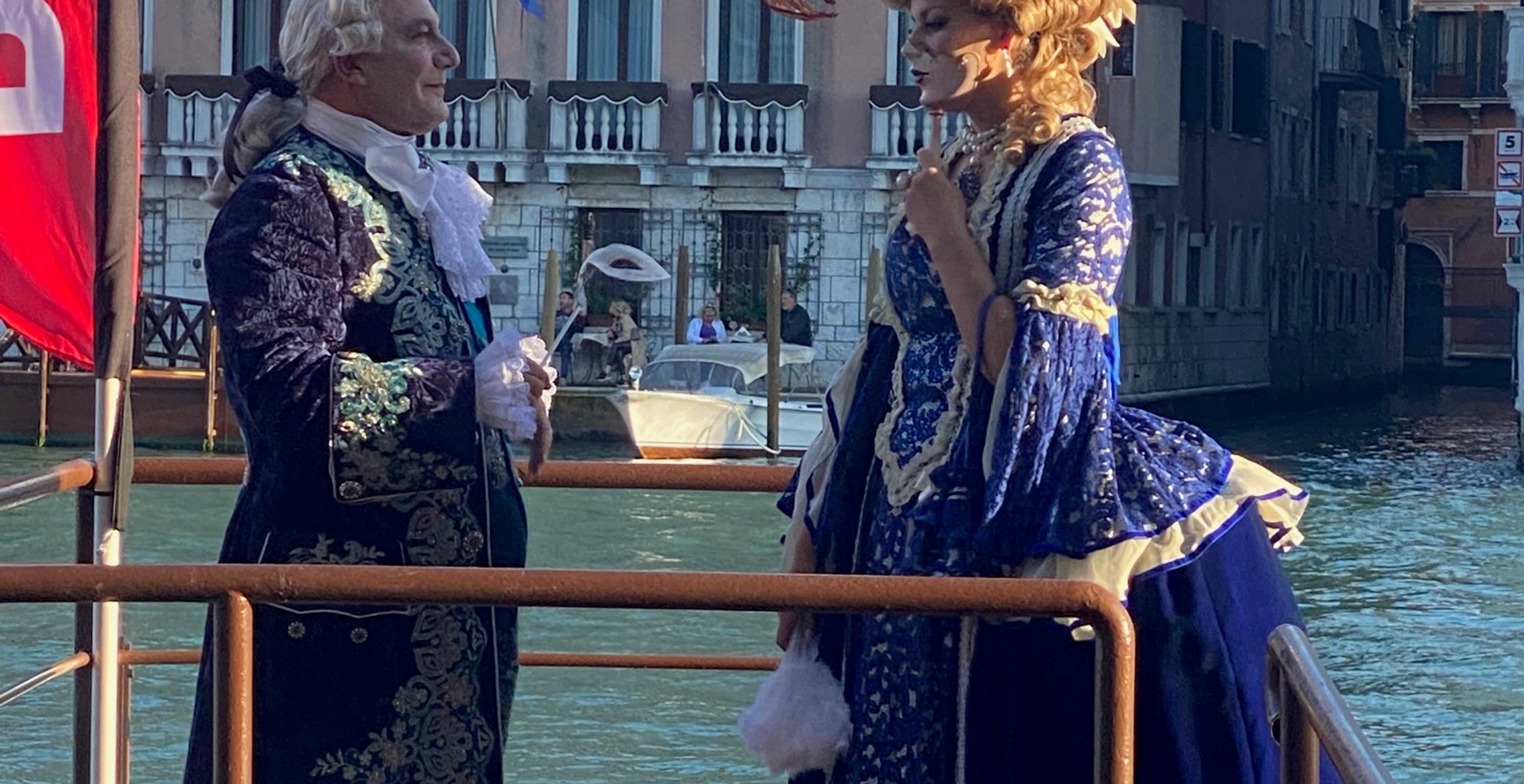 due attori vestiti in tipici abiti veneziani parlano sulla riva del canal Grande di Venezia
