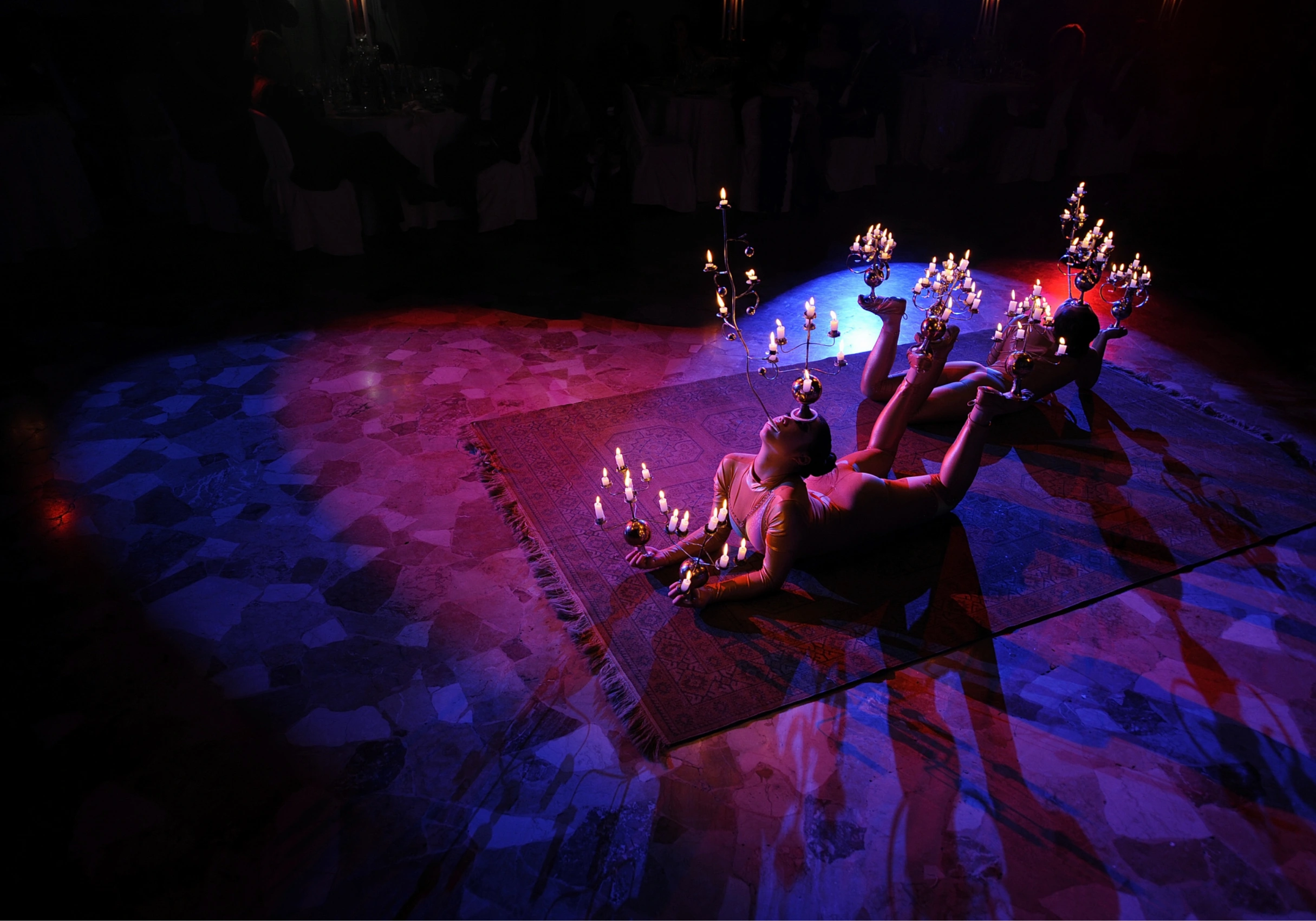 una persona sdraiata a terra su un tappeto con delle candele in mano