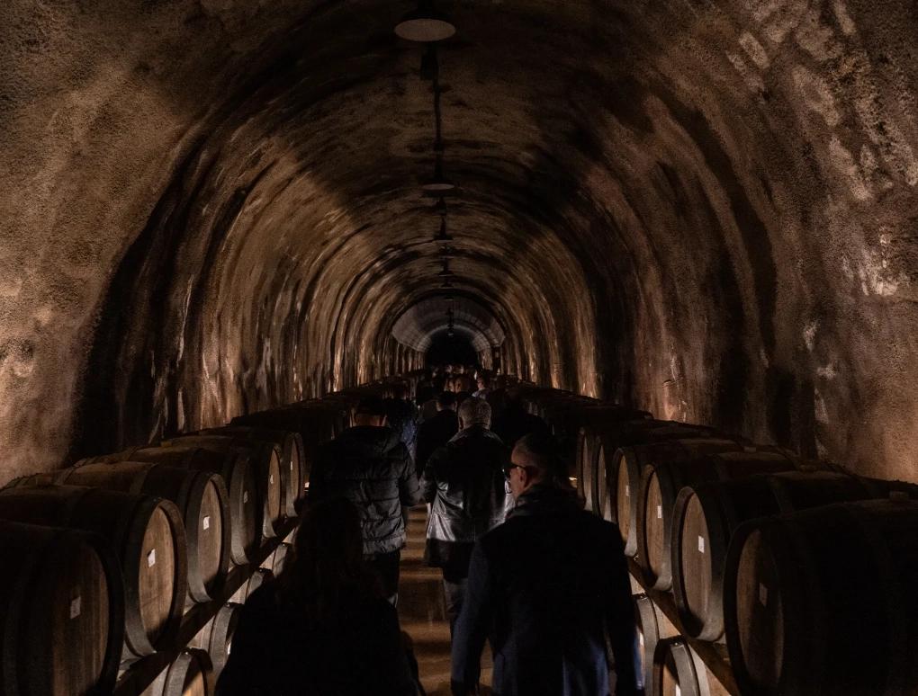 alcune persone che camminano in un tunnel con dei barili ai lati