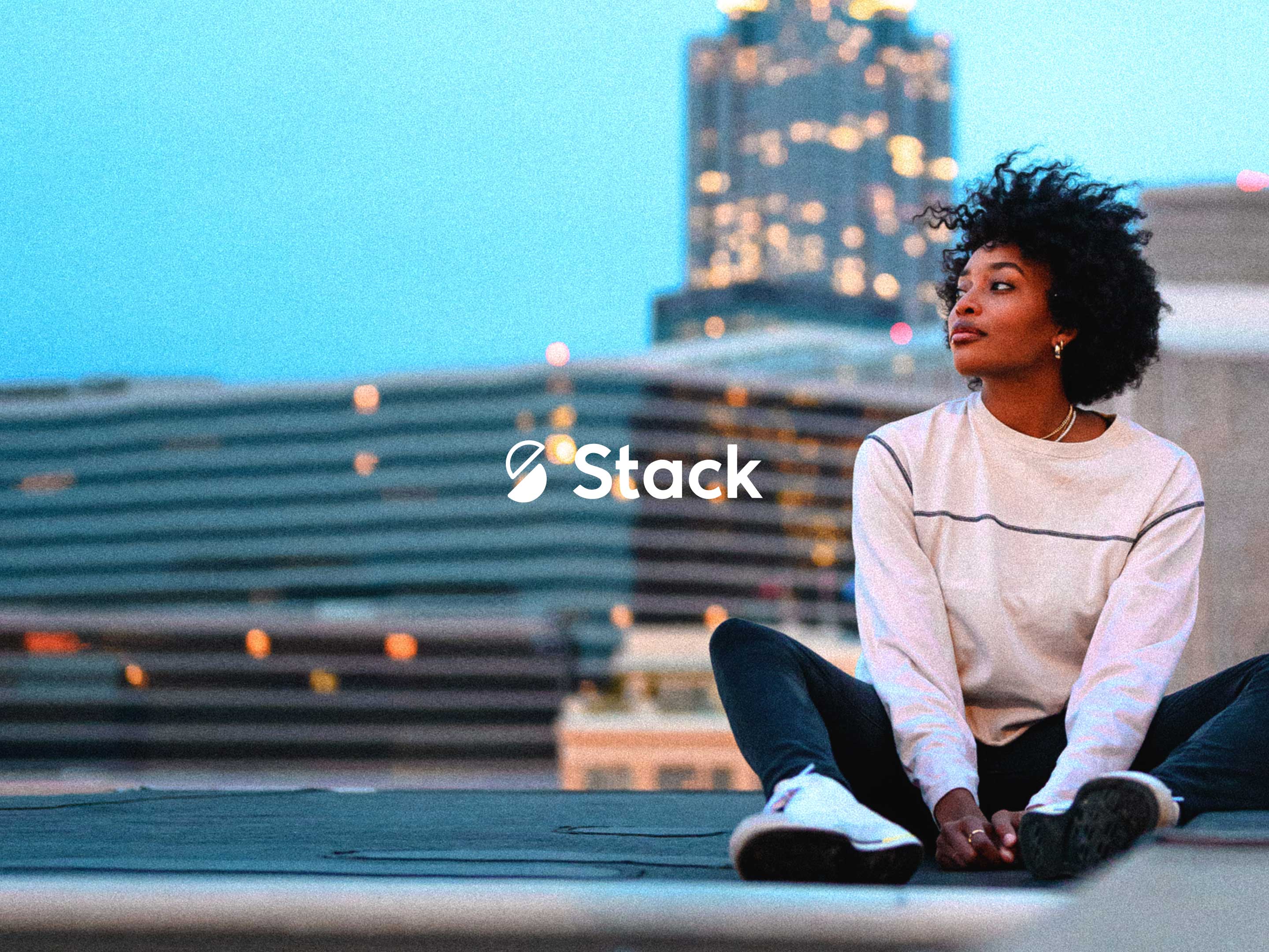 Stack logo overlaid on an image of a girl sitting on a city roof.