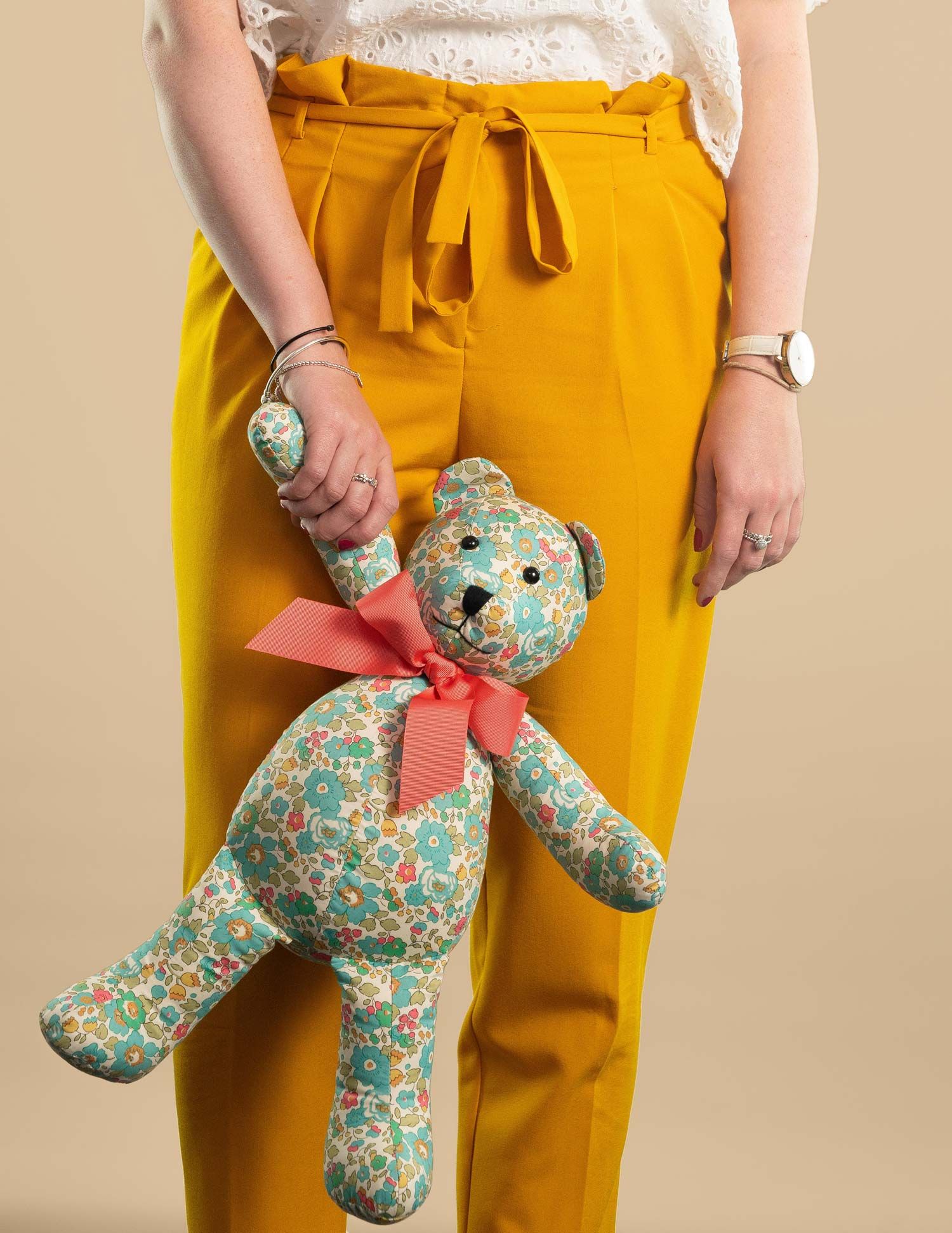 A female model holding a Grin & Bear London teddy bear in a photography studio.