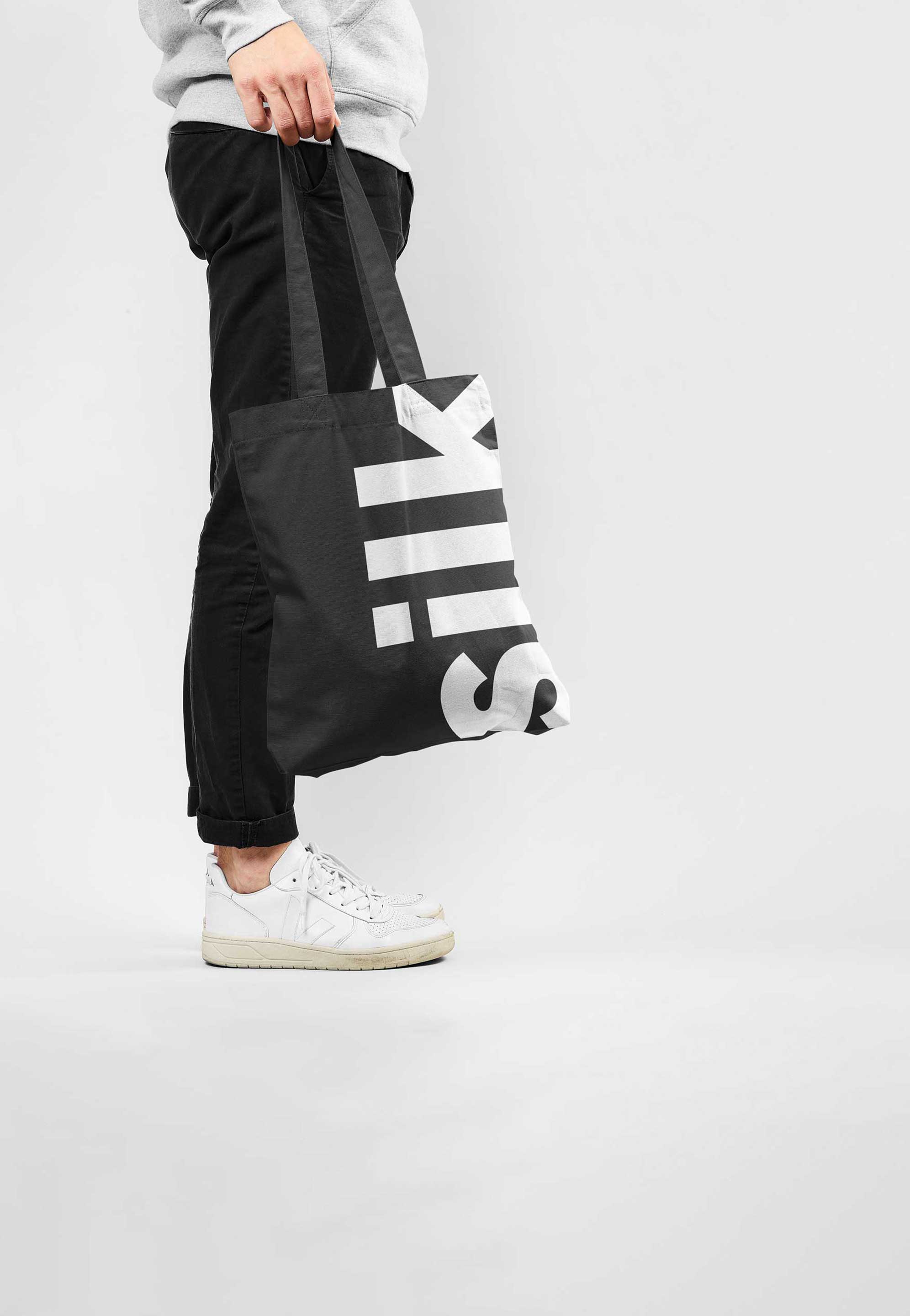 Man holding a Silk Studio branded tote bag in a photography studio.