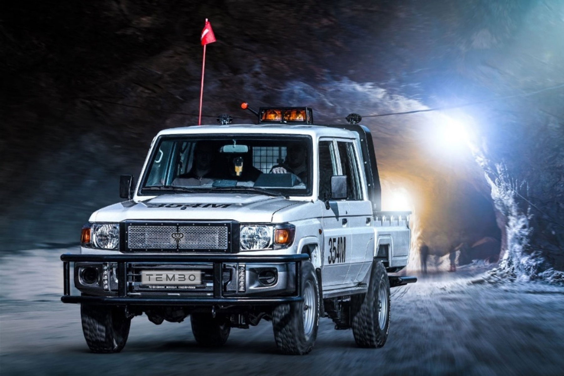 Tembo electric Land Cruiser 70 series dual-cab with roof beacons and safety flag driving through an underground mine tunnel