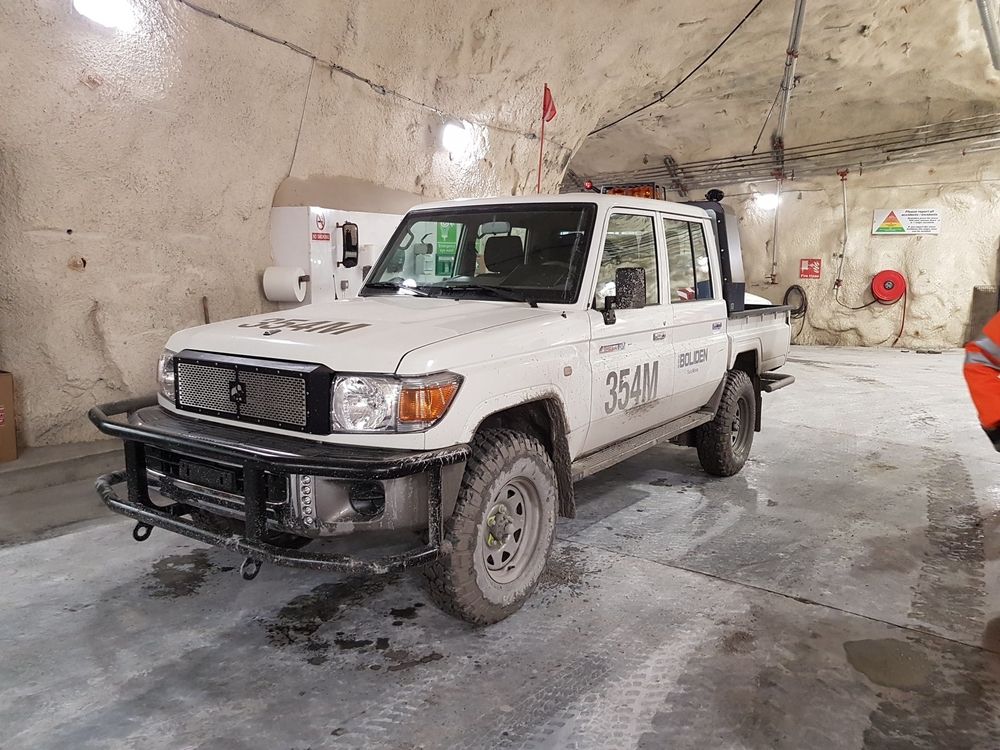 Mud-splashed Boliden Tembo 4x4 e-LV Land Cruiser dual-cab parked in a rock-walled underground mine bay