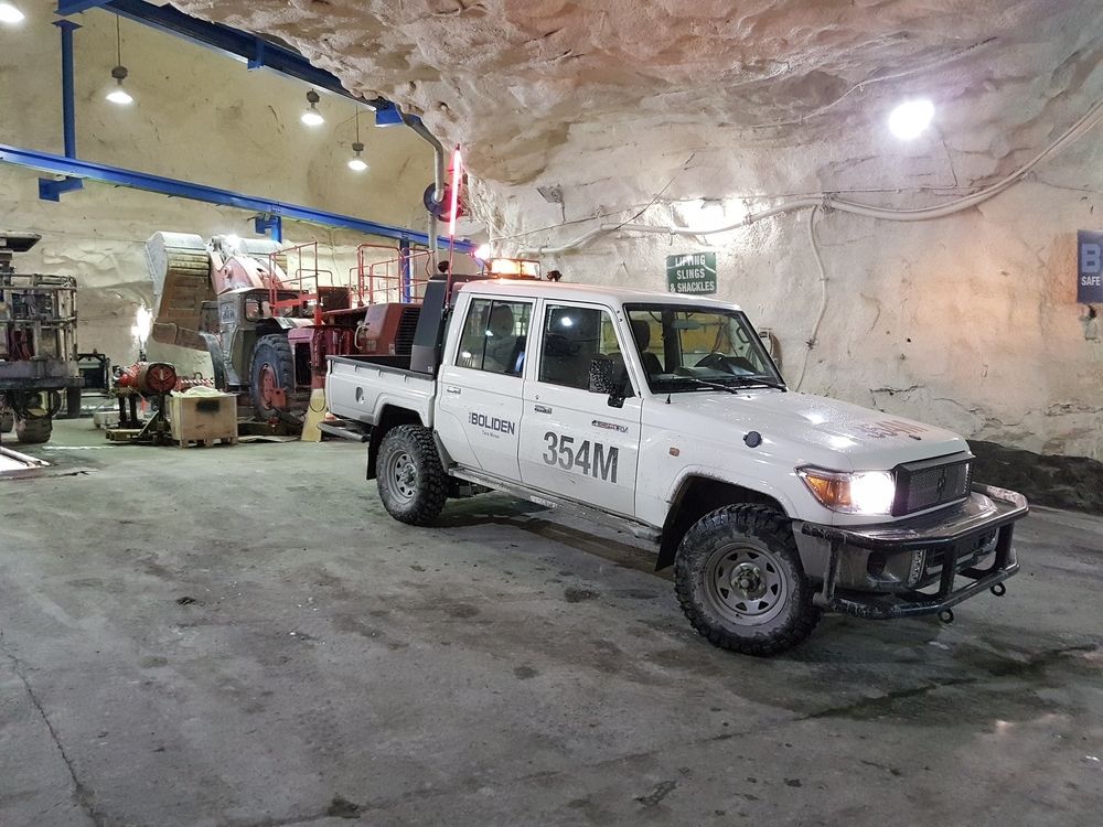 Boliden Tembo 4x4 e-LV Land Cruiser dual-cab, numbered 354M, parked in an underground mine workshop beside a loader