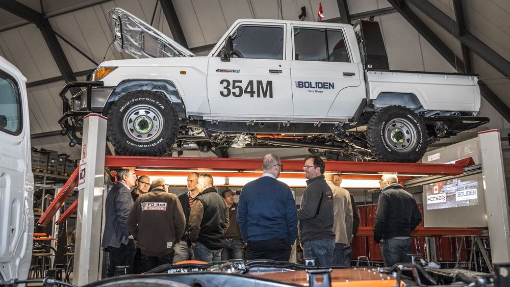 Guests gather in a workshop beneath a Tembo 4x4 e-LV dual-cab with Boliden Tara Mines decals raised on a hoist