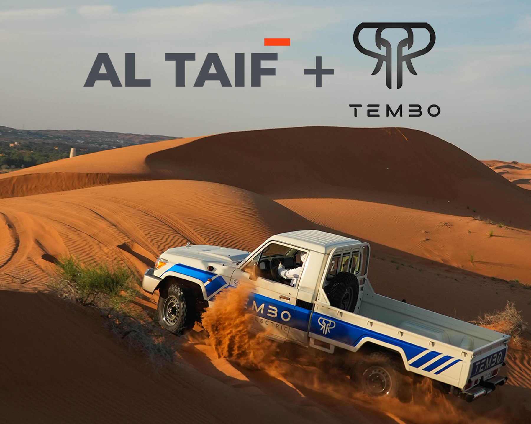 Tembo electric Land Cruiser 70 single-cab ute kicking up sand on a desert dune, with AL TAIF and Tembo logos