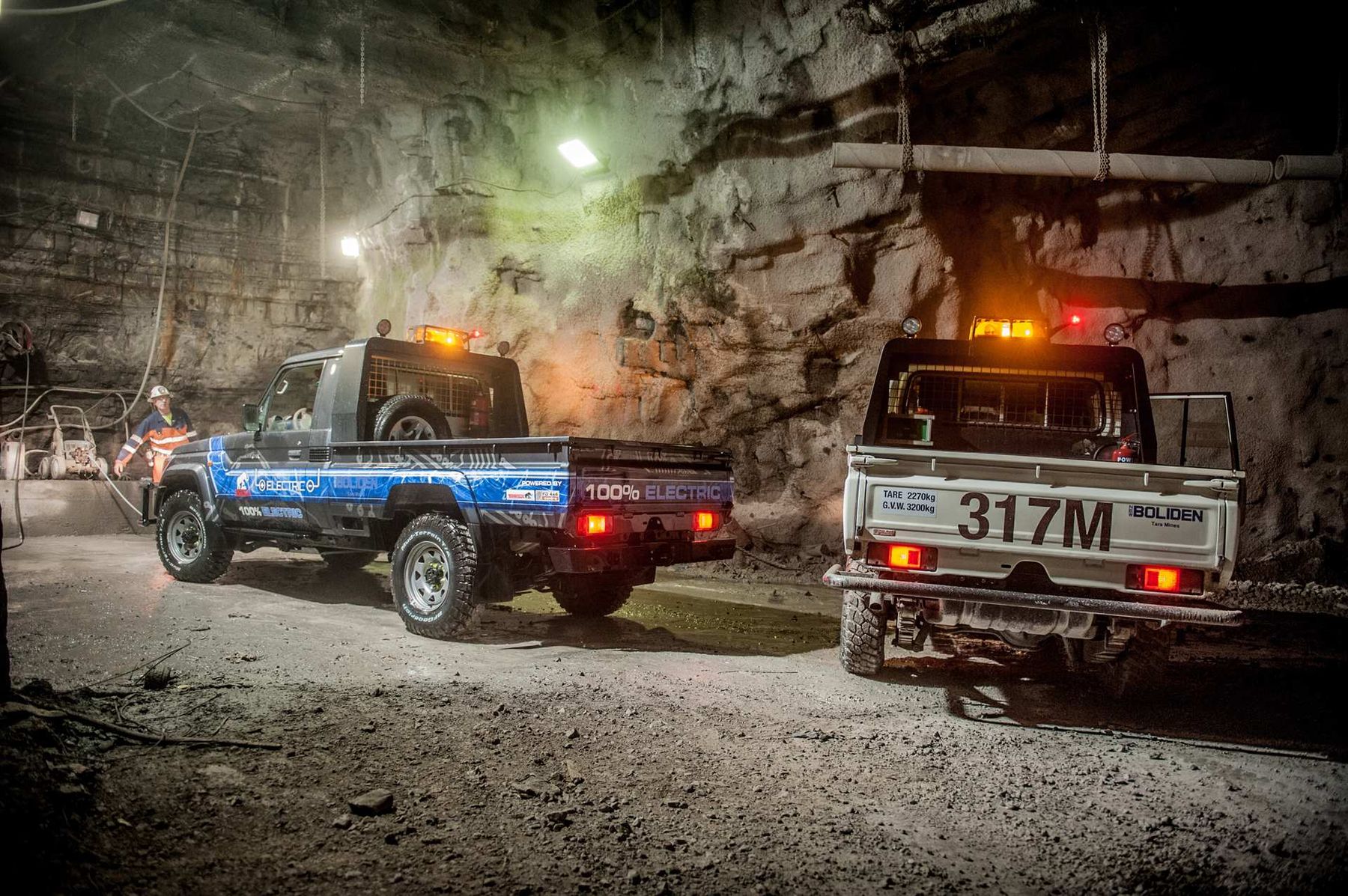 Blue '100% electric' Boliden Land Cruiser ute beside a white Boliden Tara Mines ute in an underground mine tunnel
