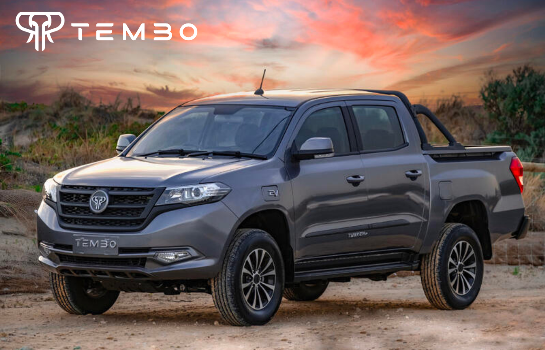 Grey Tembo Tusker dual-cab electric ute parked on a dirt track at sunset, with the Tembo logo