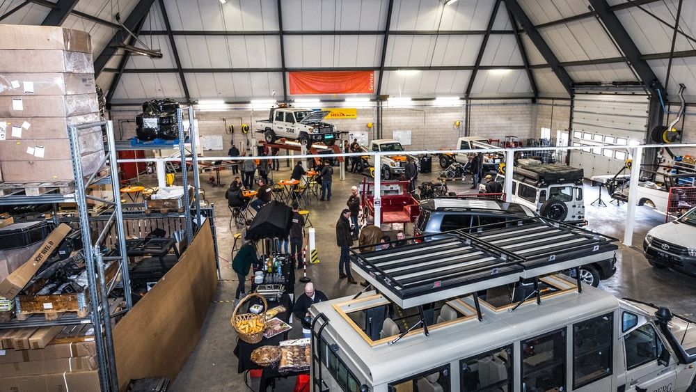 Elevated view of the busy workshop at the Tembo 4x4 e-LV launch, with guests, catering and Land Cruisers on display