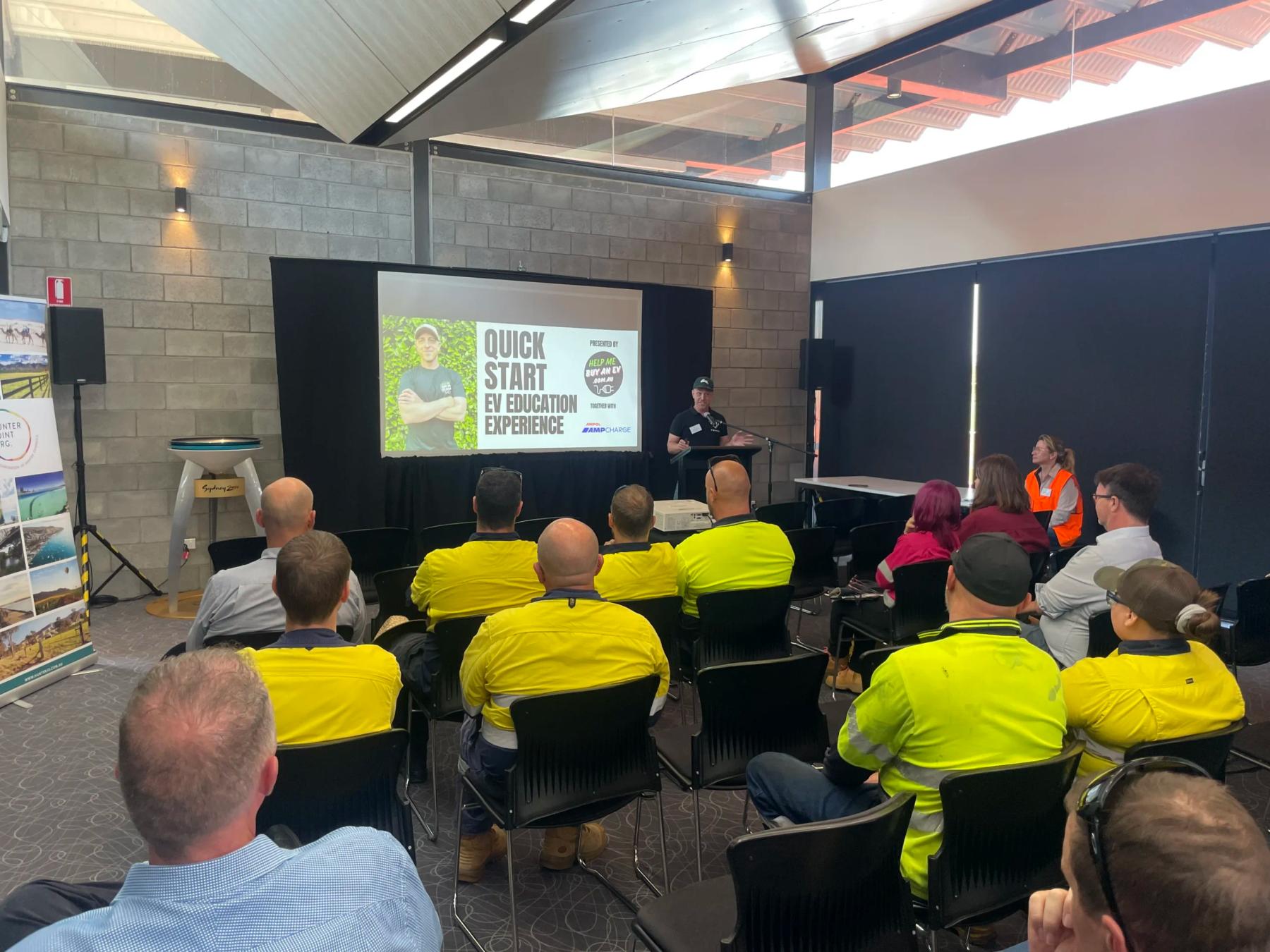 Speaker presenting a Quick Start EV Education Experience session to an audience in hi-vis workwear