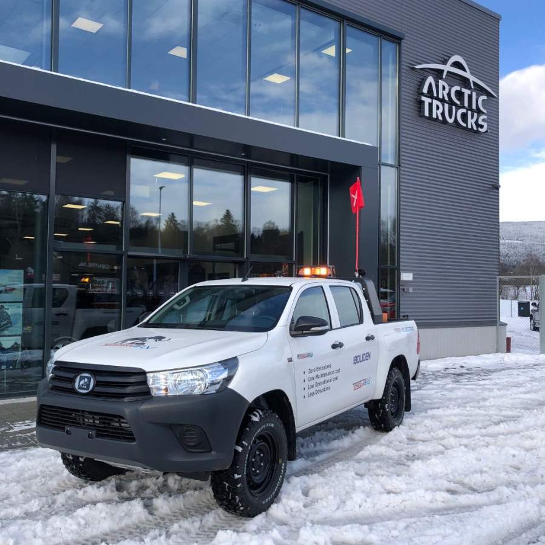 Boliden-branded Tembo 4x4 e-LV Hilux dual-cab parked in snow outside an Arctic Trucks building