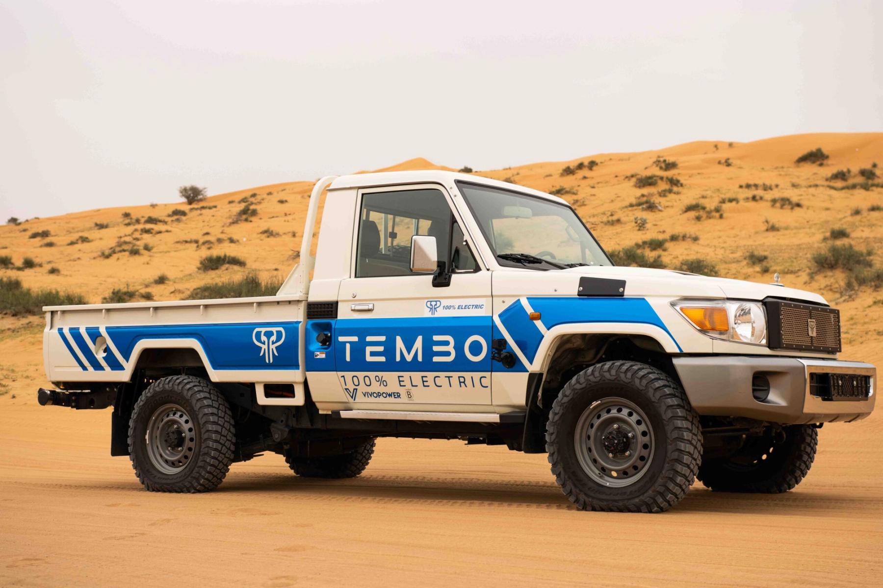 Tembo-liveried 100% electric Toyota Land Cruiser 70 single-cab ute parked among desert sand dunes