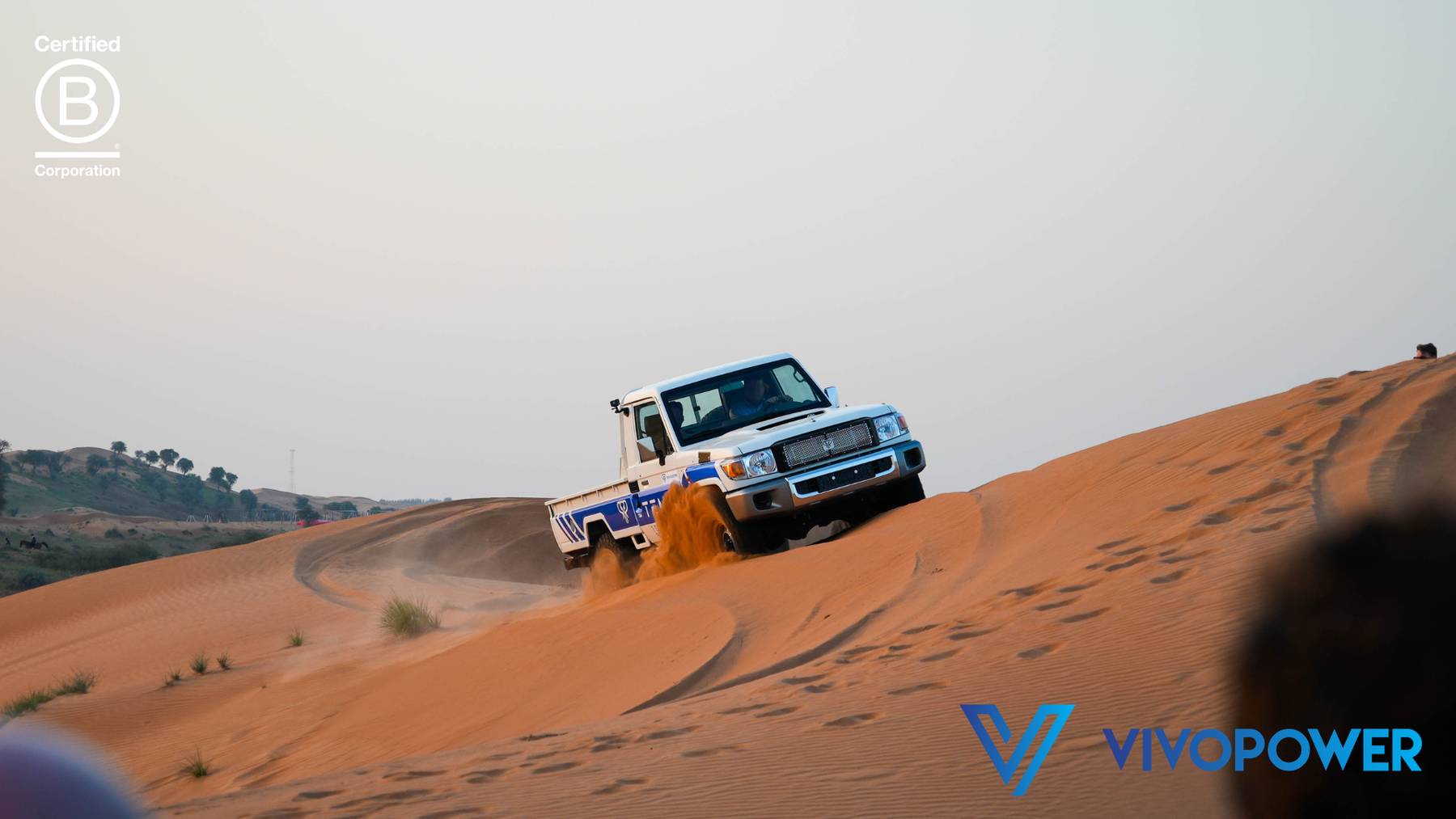 Tembo-liveried electric Land Cruiser single-cab climbing a red sand dune with sand spraying from its wheels