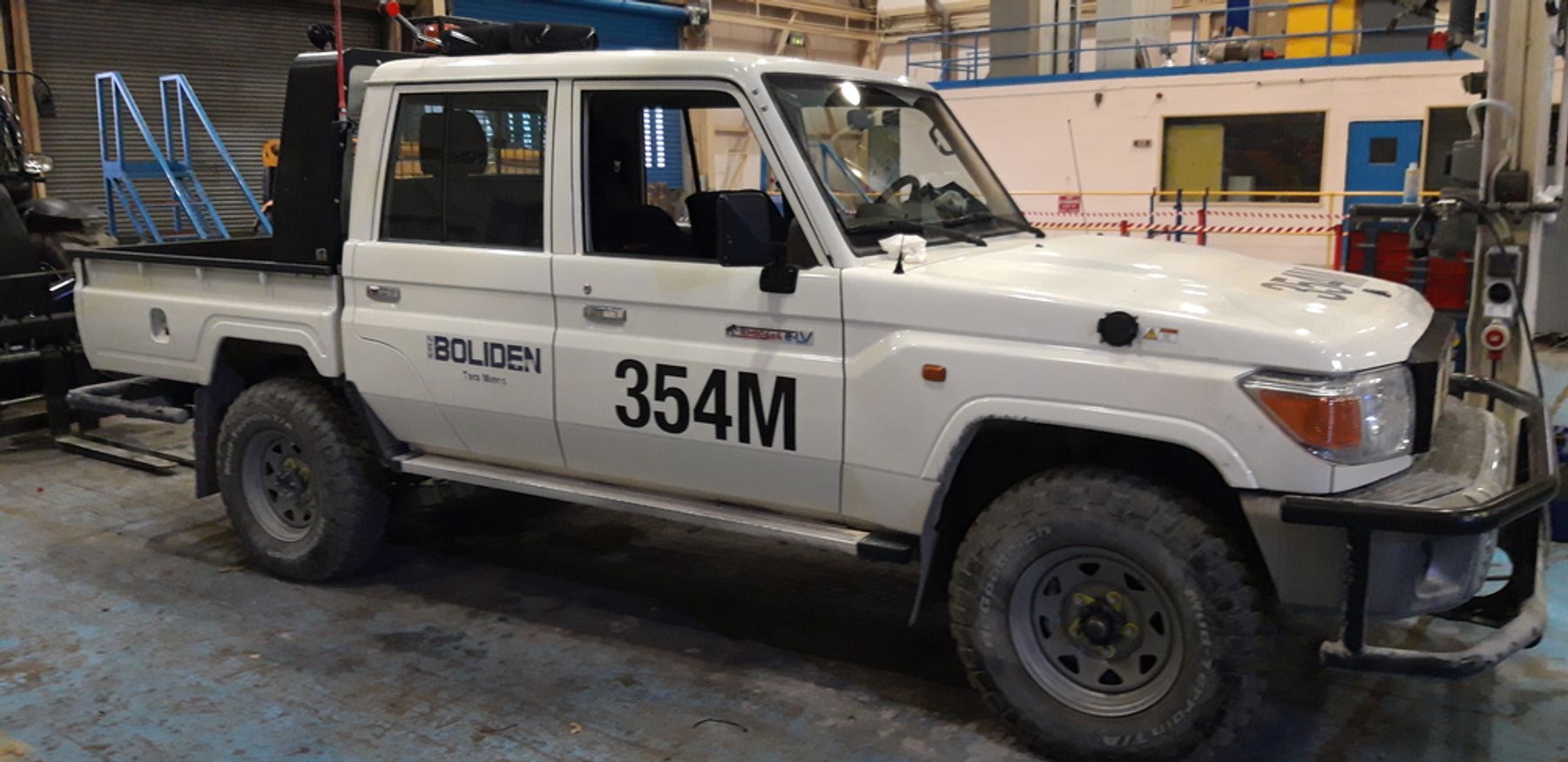 Side view of the Boliden Tara Mines Tembo 4x4 e-LV, a converted Land Cruiser 70 series dual-cab, in a workshop