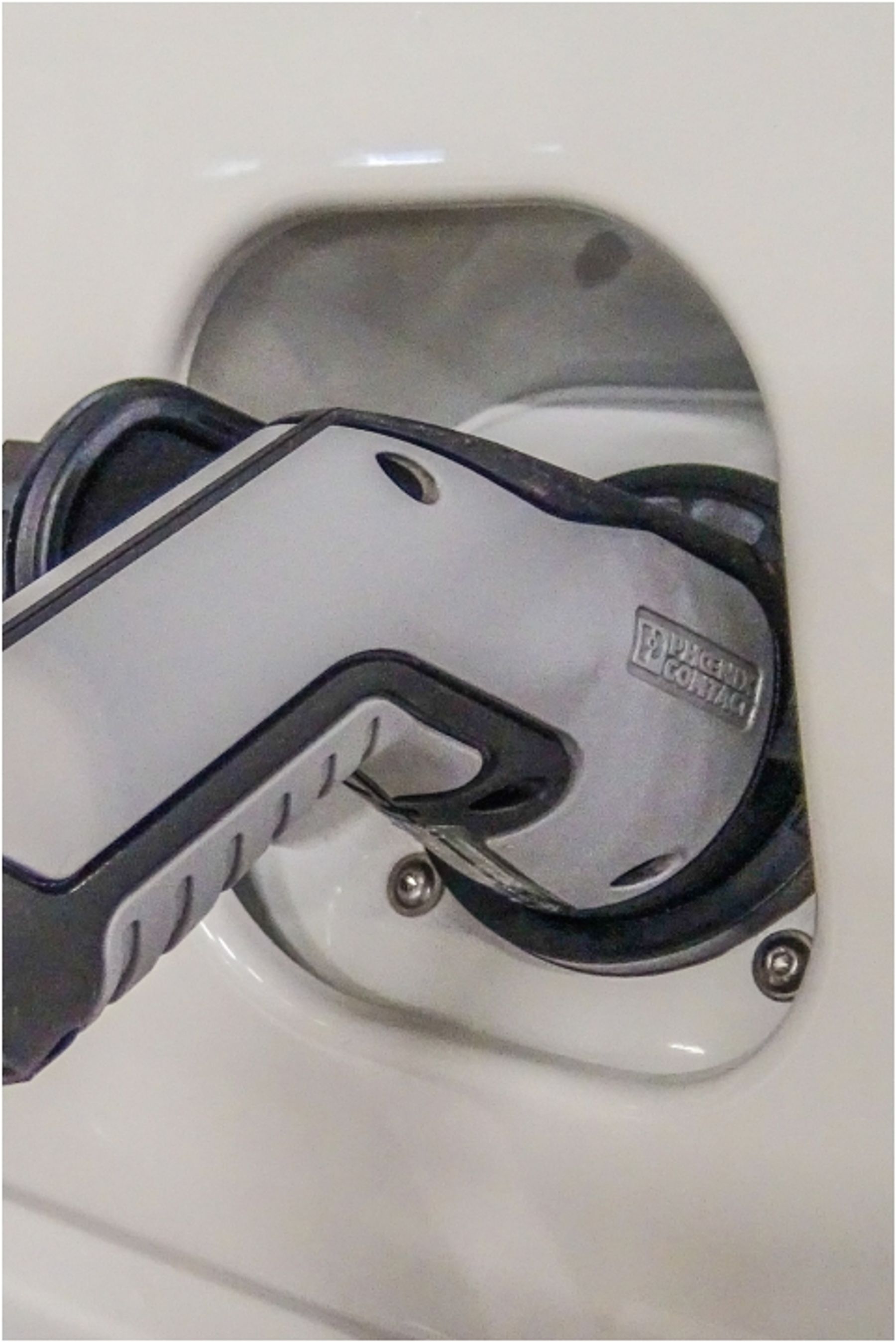 Close-up of a charging connector plugged into the charge port of a white electric vehicle