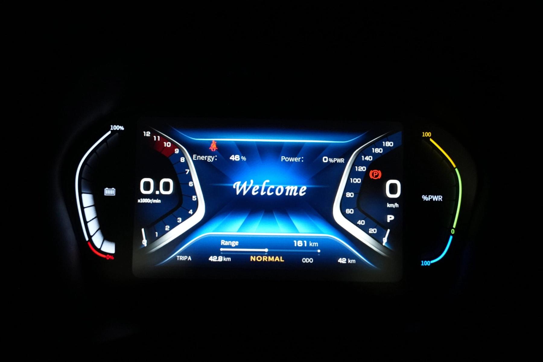 Electric ute instrument cluster glowing in the dark with a welcome message, 46% energy and 161 km range