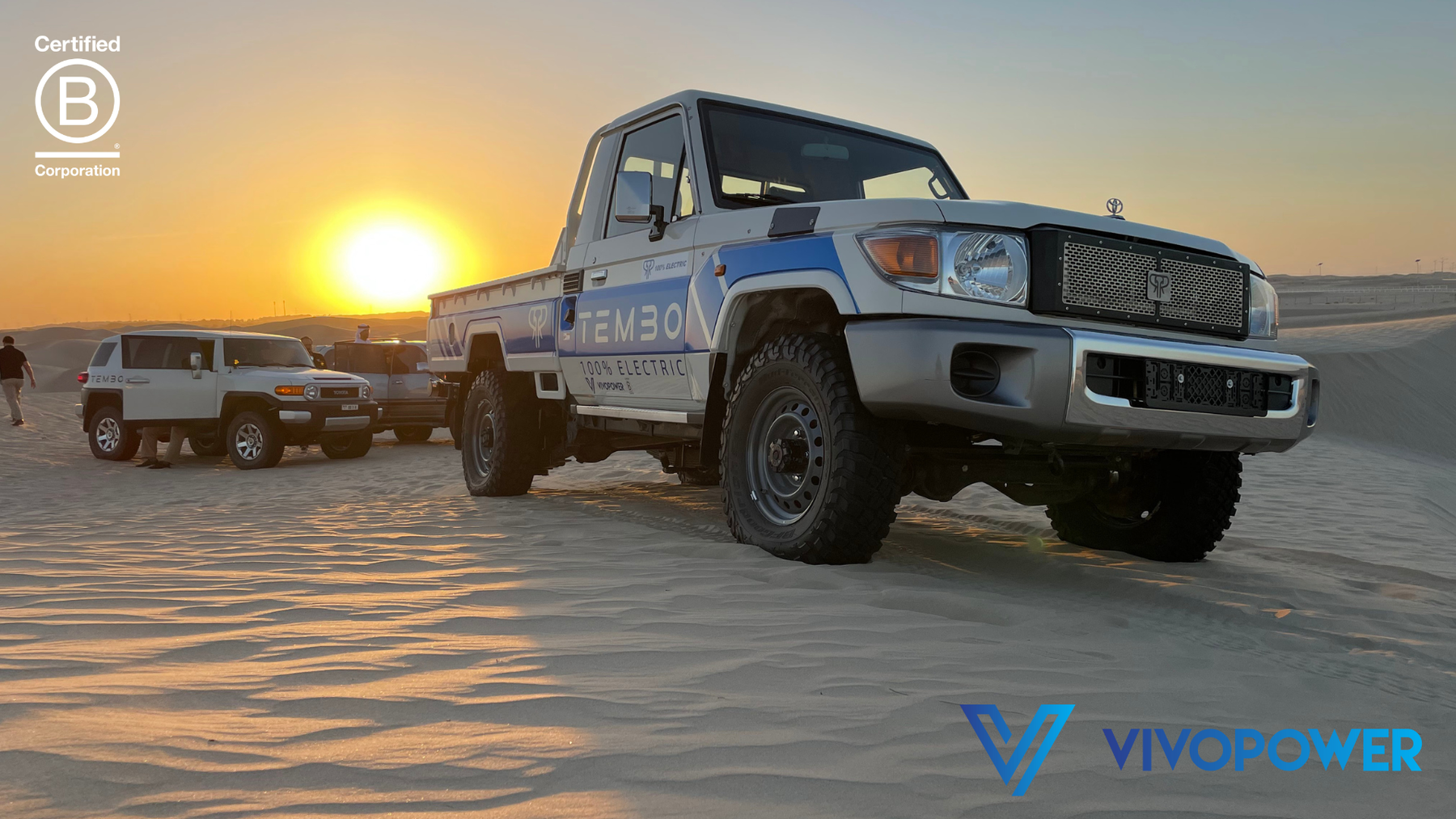 Tembo-liveried 100% electric Land Cruiser 70 series pickup on desert sand at sunset, with VivoPower and B Corp logos