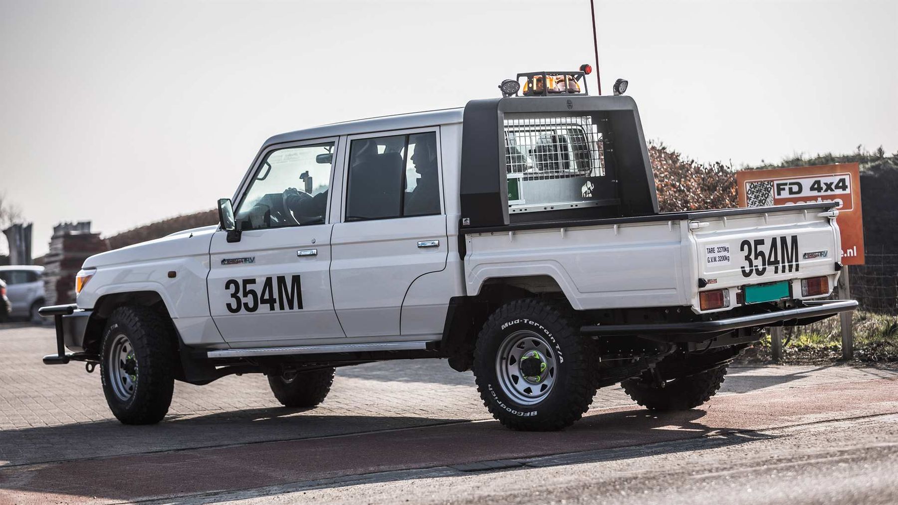 Rear three-quarter view of a Tembo 4x4 e-LV dual-cab Land Cruiser with roof beacons, cargo cage and fleet number 354M