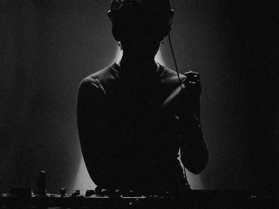 A silhouetted Andy Garvey performs with their DJ decks.
