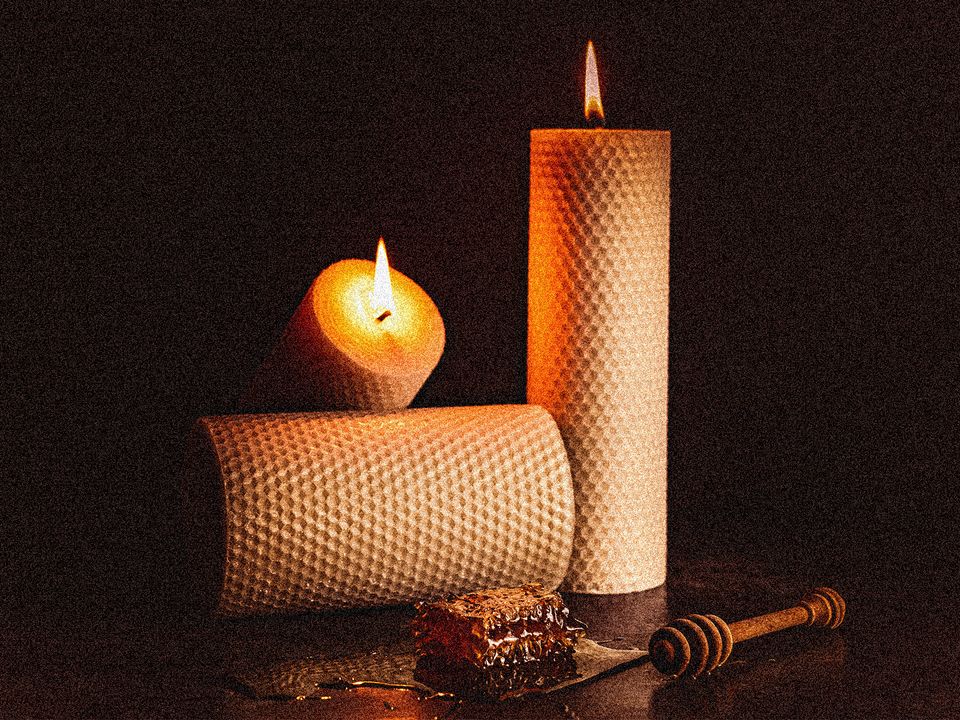 Beeswax candles and honeycomb artistically placed on a table. 