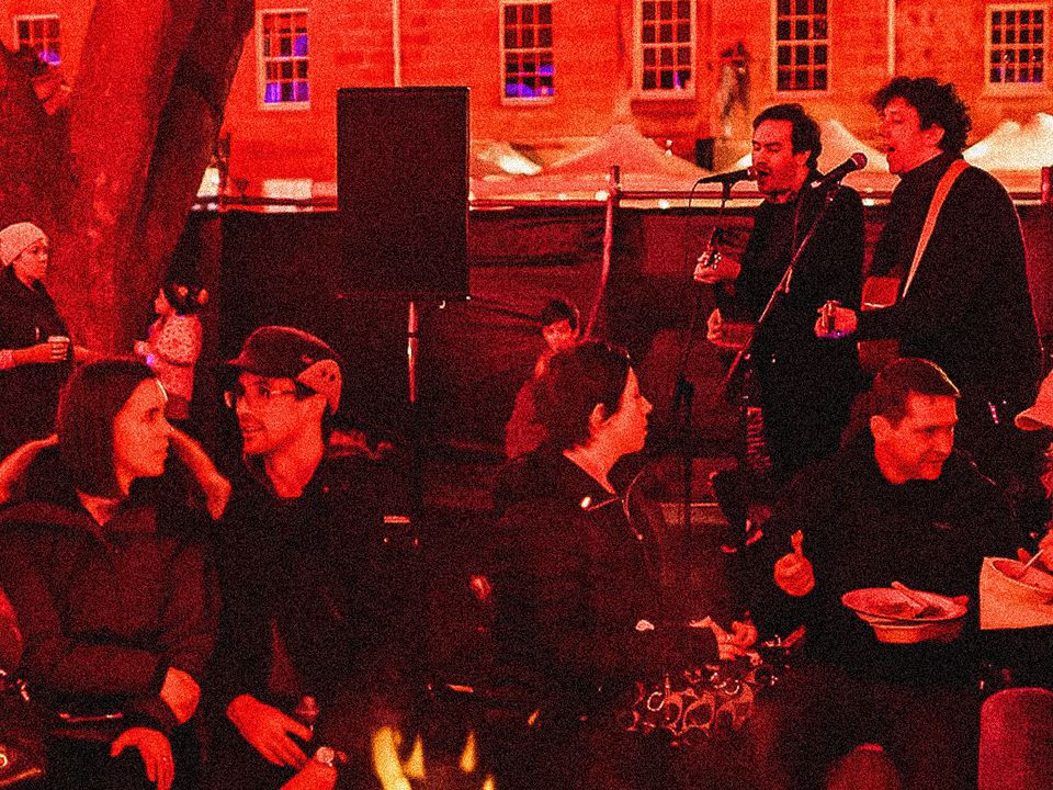 A group of people sitting around a fire, enjoying the music at Winter Feast.