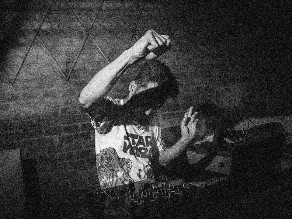 Y-DRA performs with his DJ setup, hands in the air.