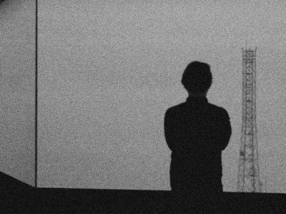 A silhouette of a person stands in front of a projected screen.