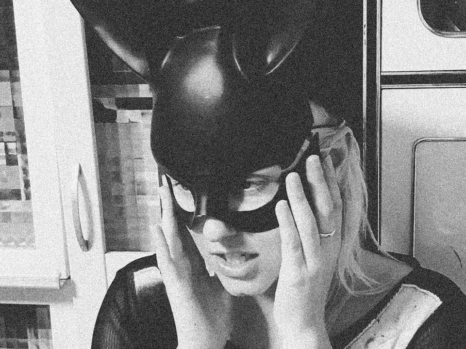 Estee Louder wears a black rabbit-like mask.
