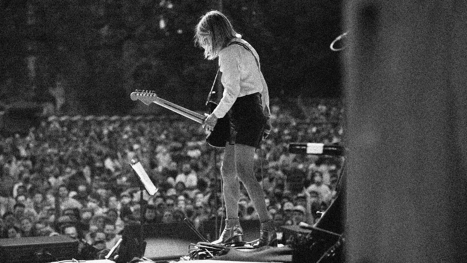 Kim Gordon on stage performs in-front of a large crowd.
