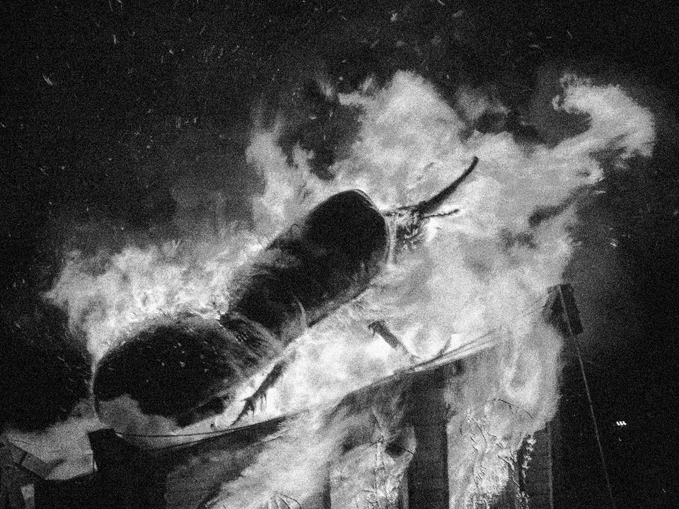 A large beetle effigy burns, with raging flames surrounding the object.
