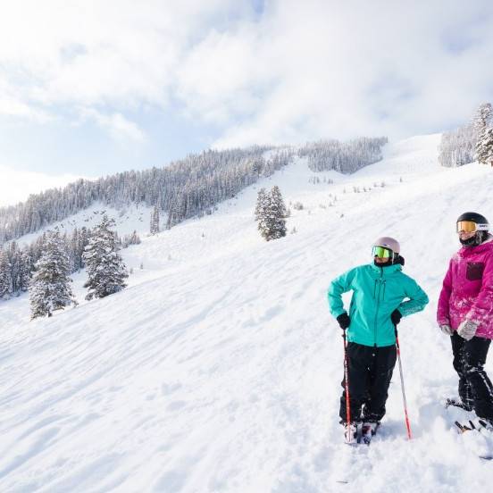 A skier and a snowboarder standing on a snowy trail