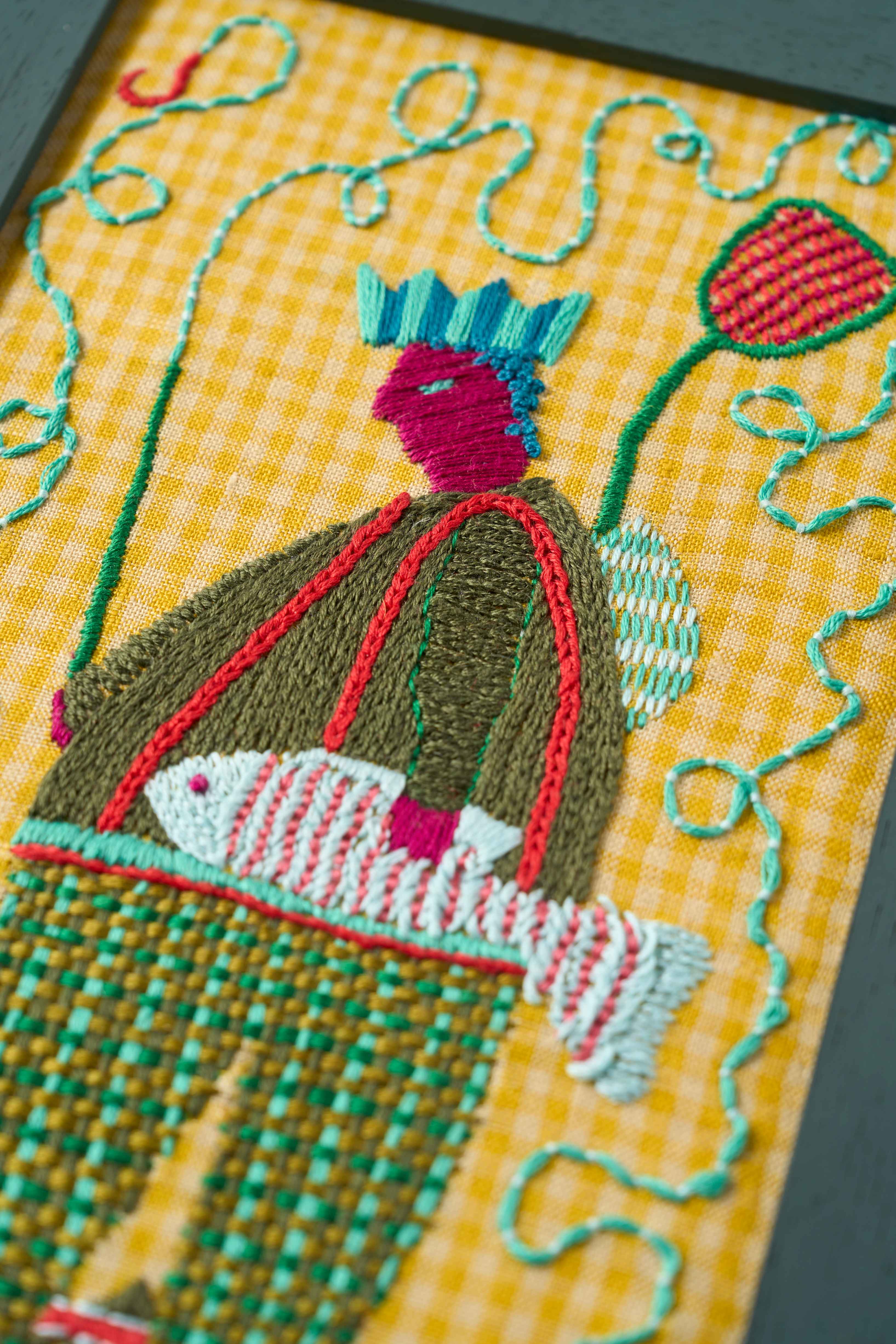 Close up of the limited edition embroidery The Catch from The Fabled Thread on yellow check fabric in a painted frame