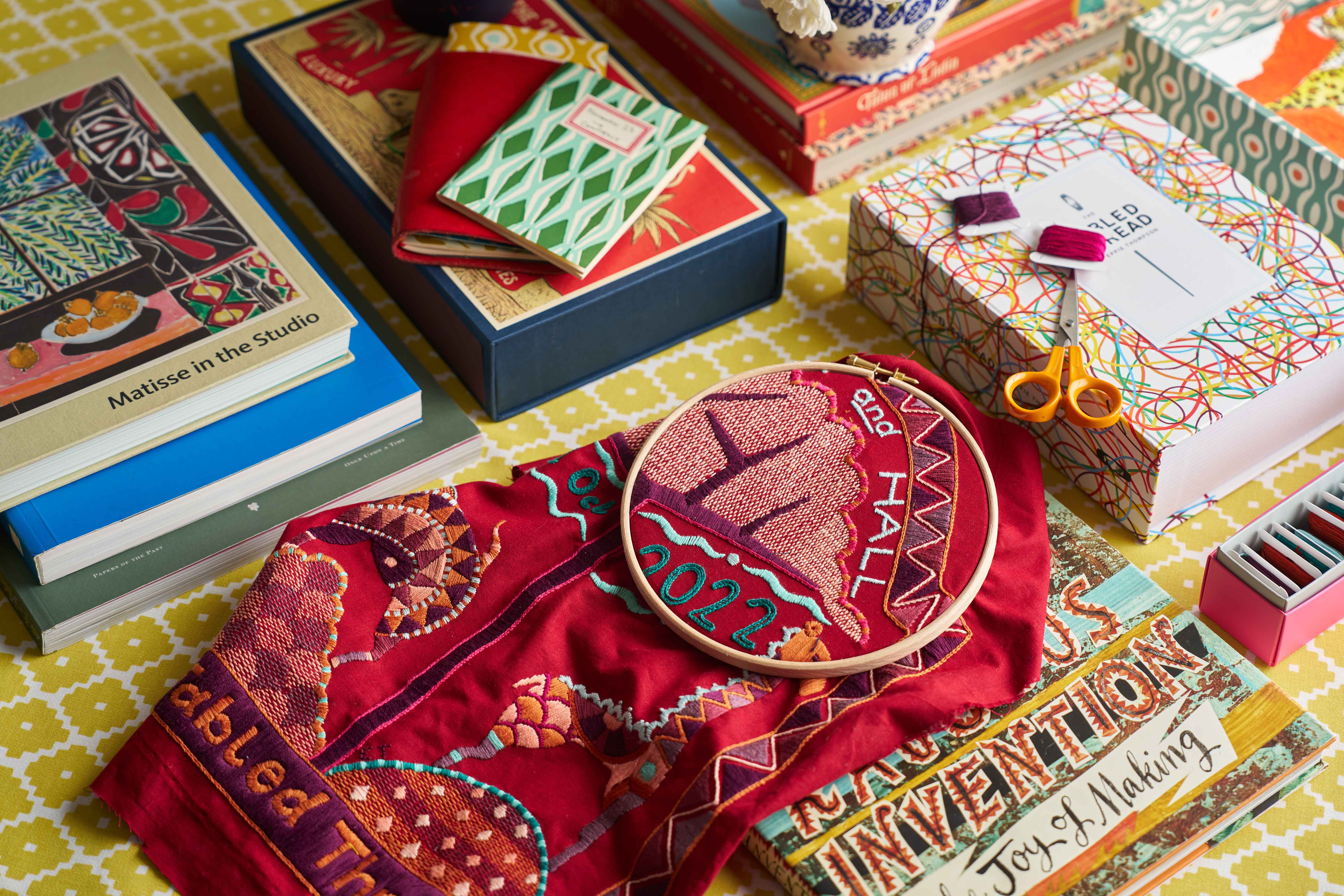 Embroidery art in hoop on a table with books