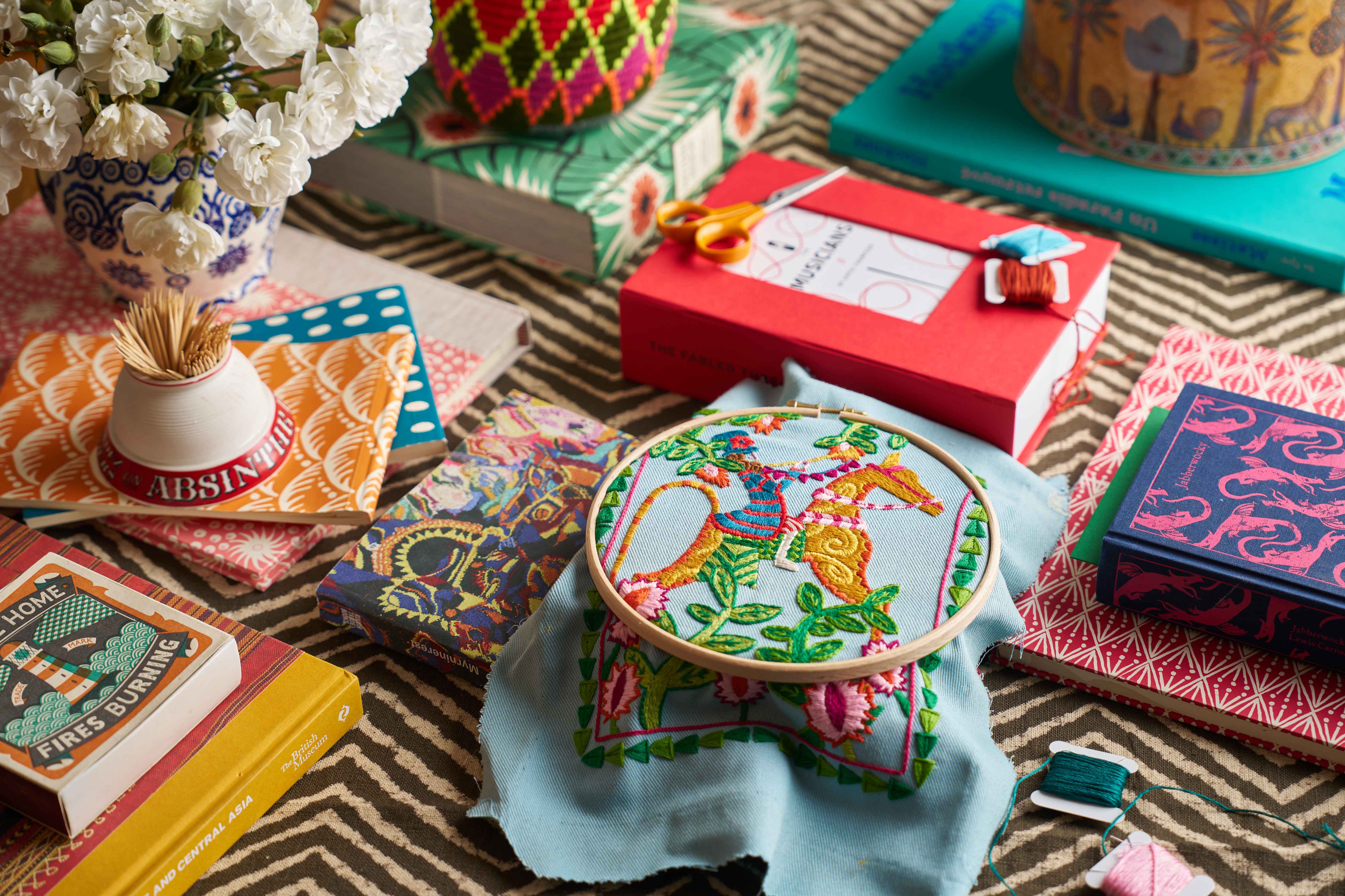 Horse and Rider embroidery kit in hoop on a table surrounded by colourful books