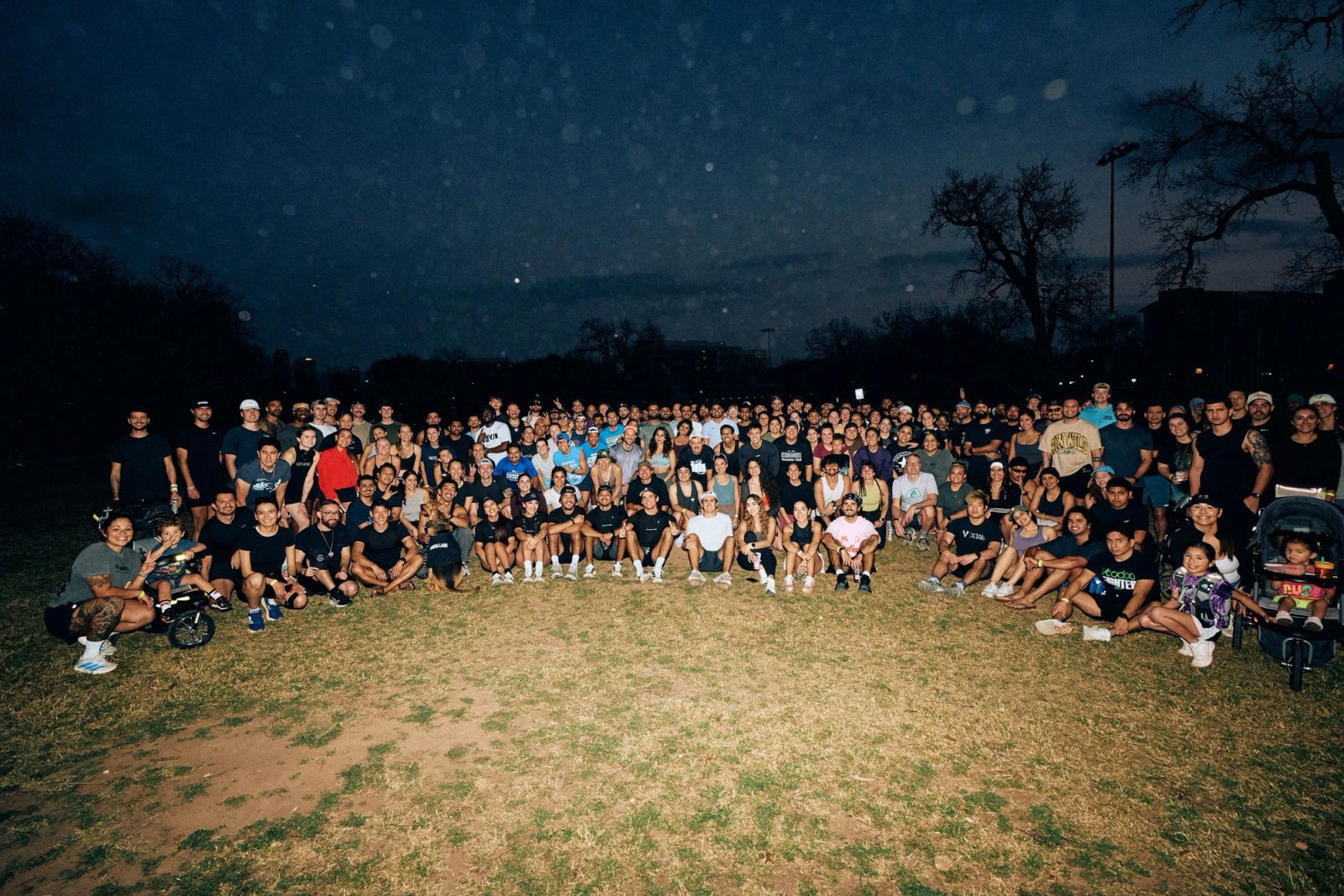 A wide-angle drone photograph capturing a crowd of over 600 wellness community members at an outdoor event