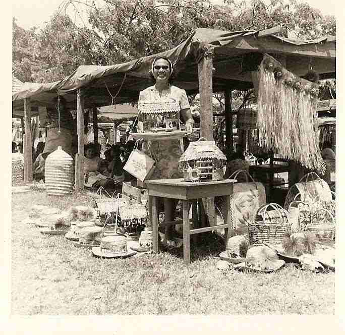 My grandmother at the markets, surrounded by her handiwork.